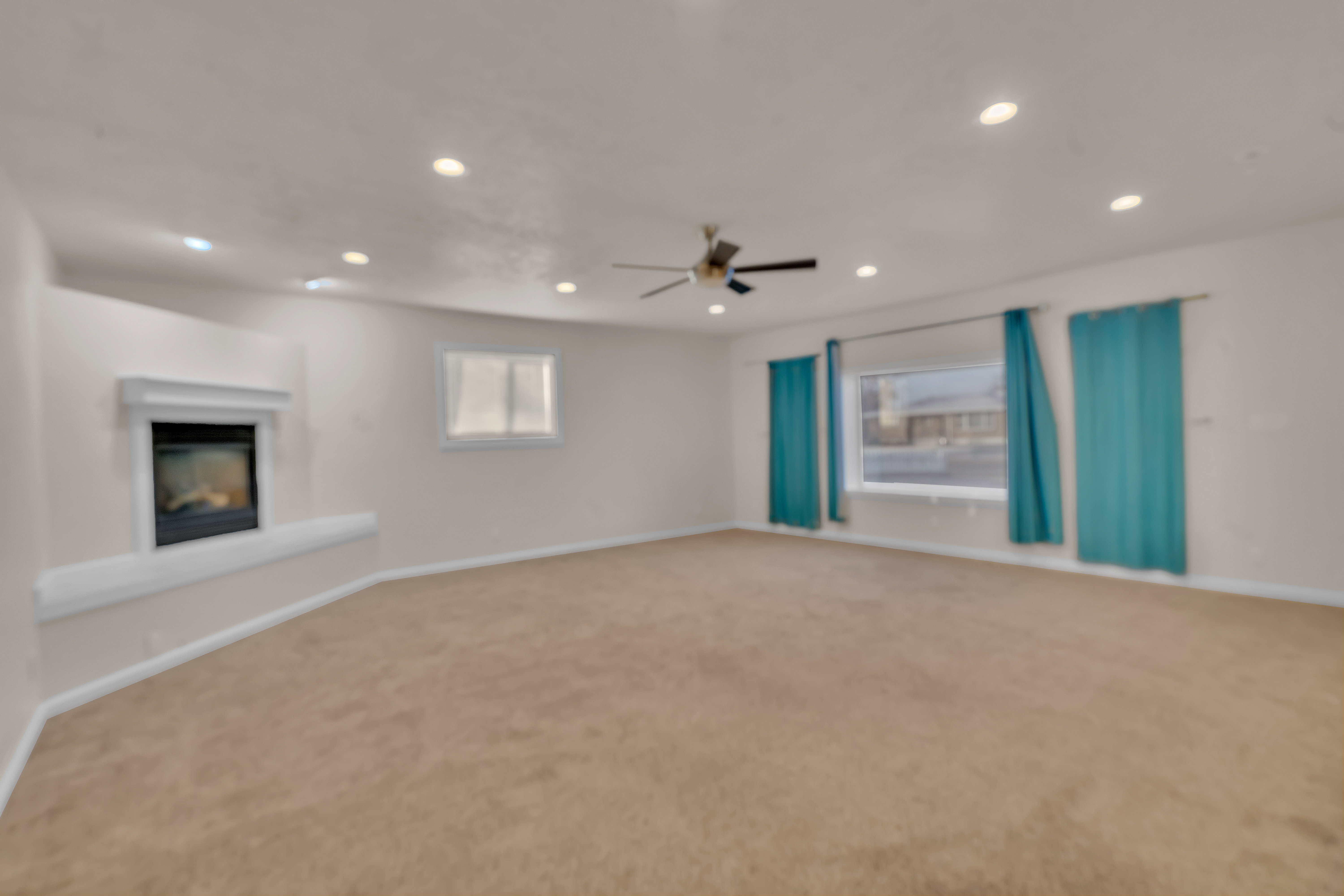 Carpeted living space featuring a built-in fireplace with a hearth, multiple recessed lights, a ceiling fan, and a large window with two smaller windows