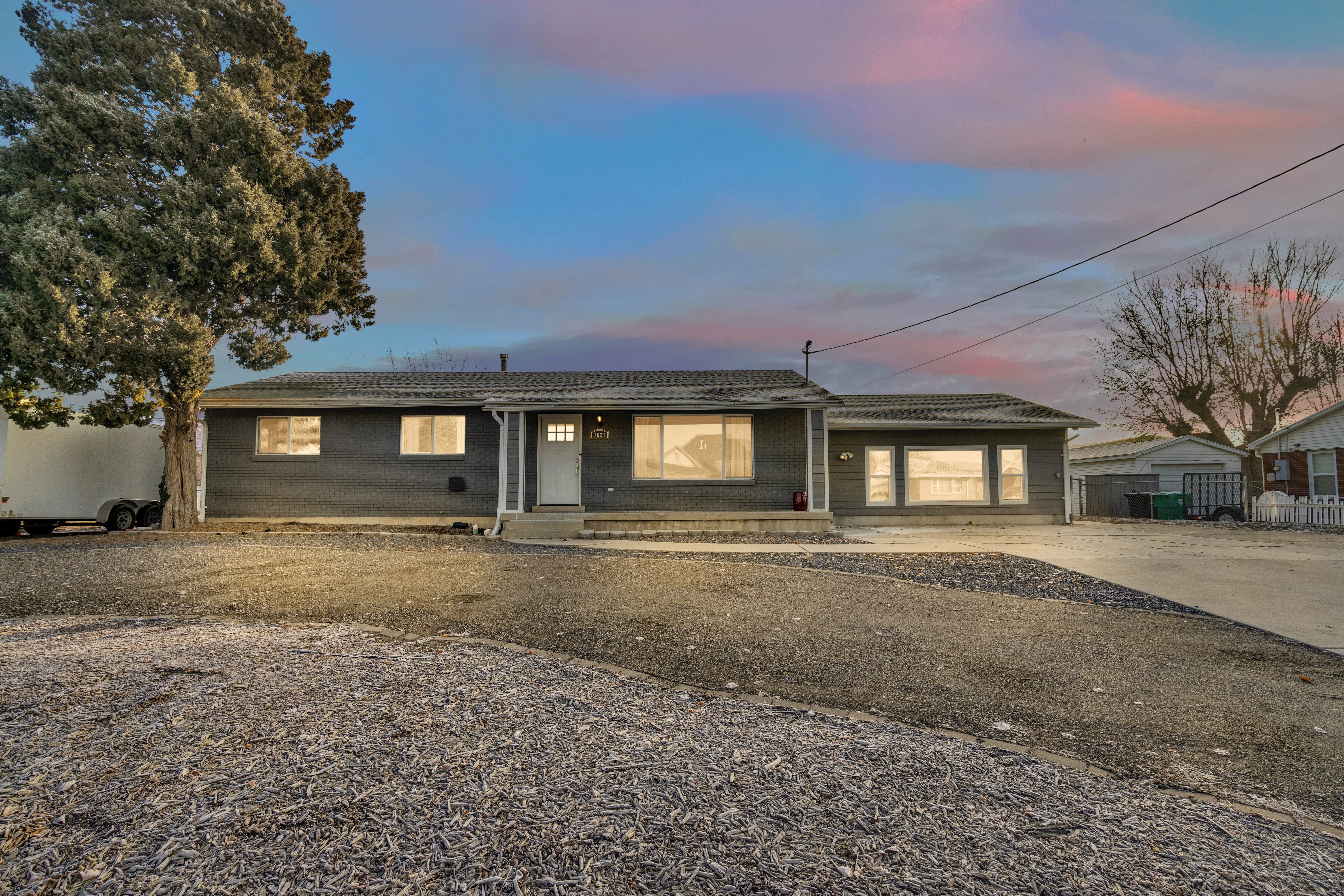 Ranch-style residence featuring a dark gray exterior, white entry door, and multiple windows