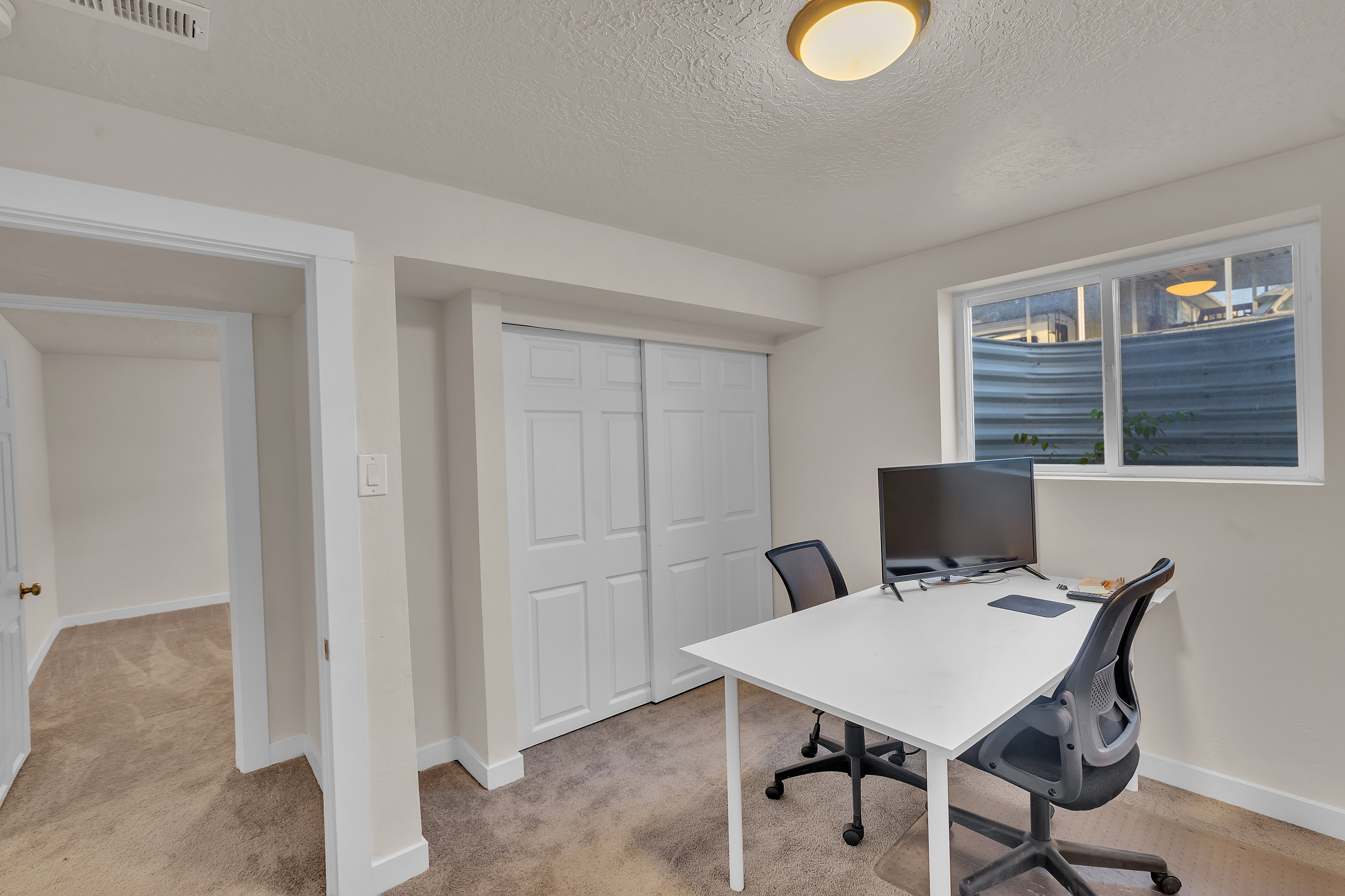 Versatile room featuring a window, neutral carpet, and white sliding closet doors