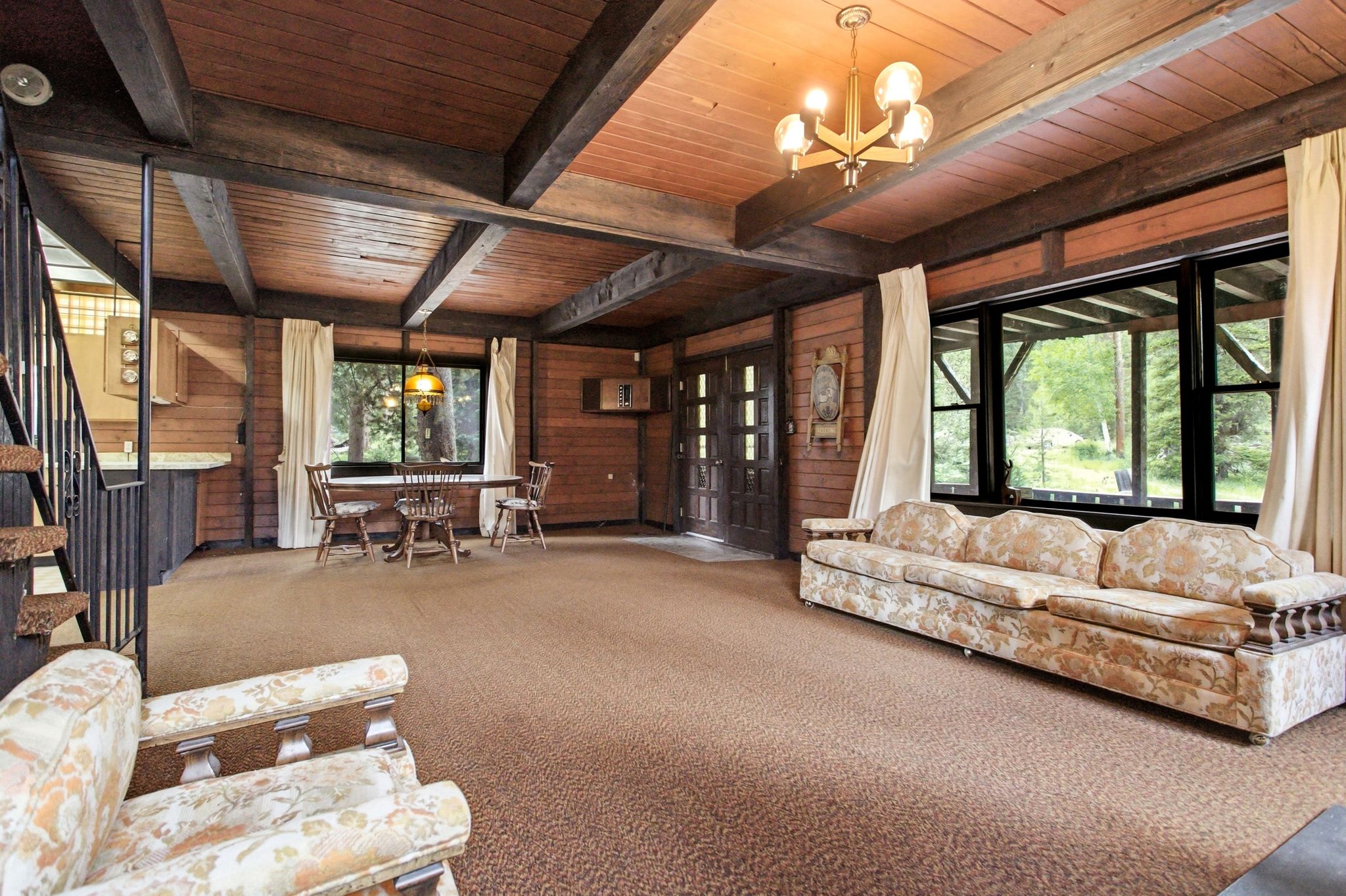 Spacious living area featuring exposed wood beams, wood paneling, and a wood-finish ceiling
