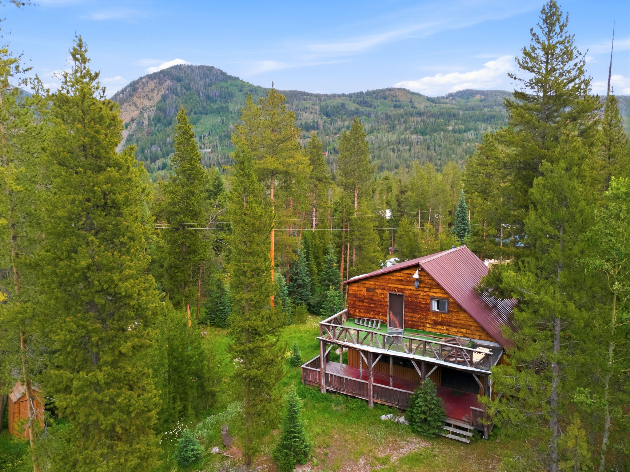 Wood-sided home featuring a red metal roof and two-story wrap-around deck
