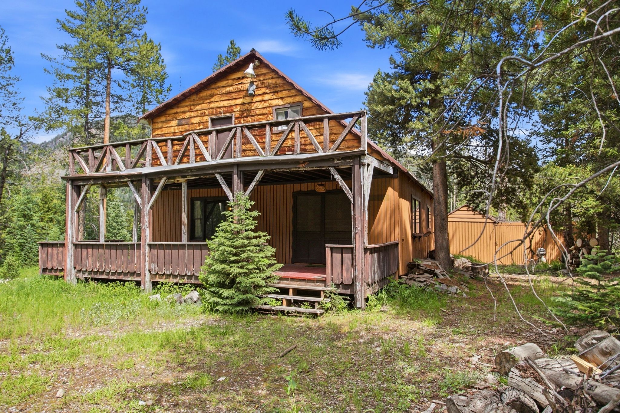 Wood-sided cabin featuring a covered porch and second-story balcony