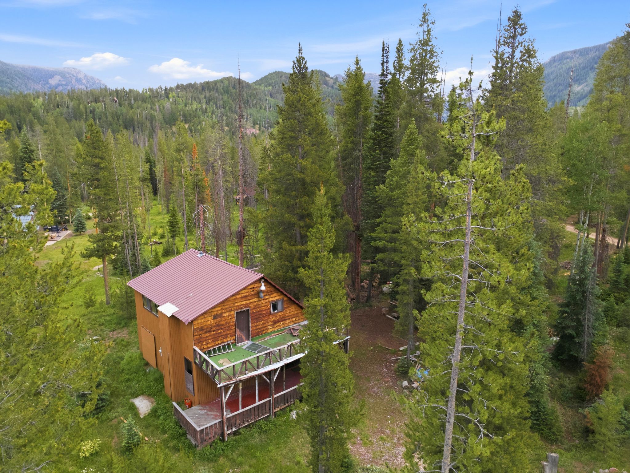 Wood-sided cabin featuring a metal roof and an elevated porch