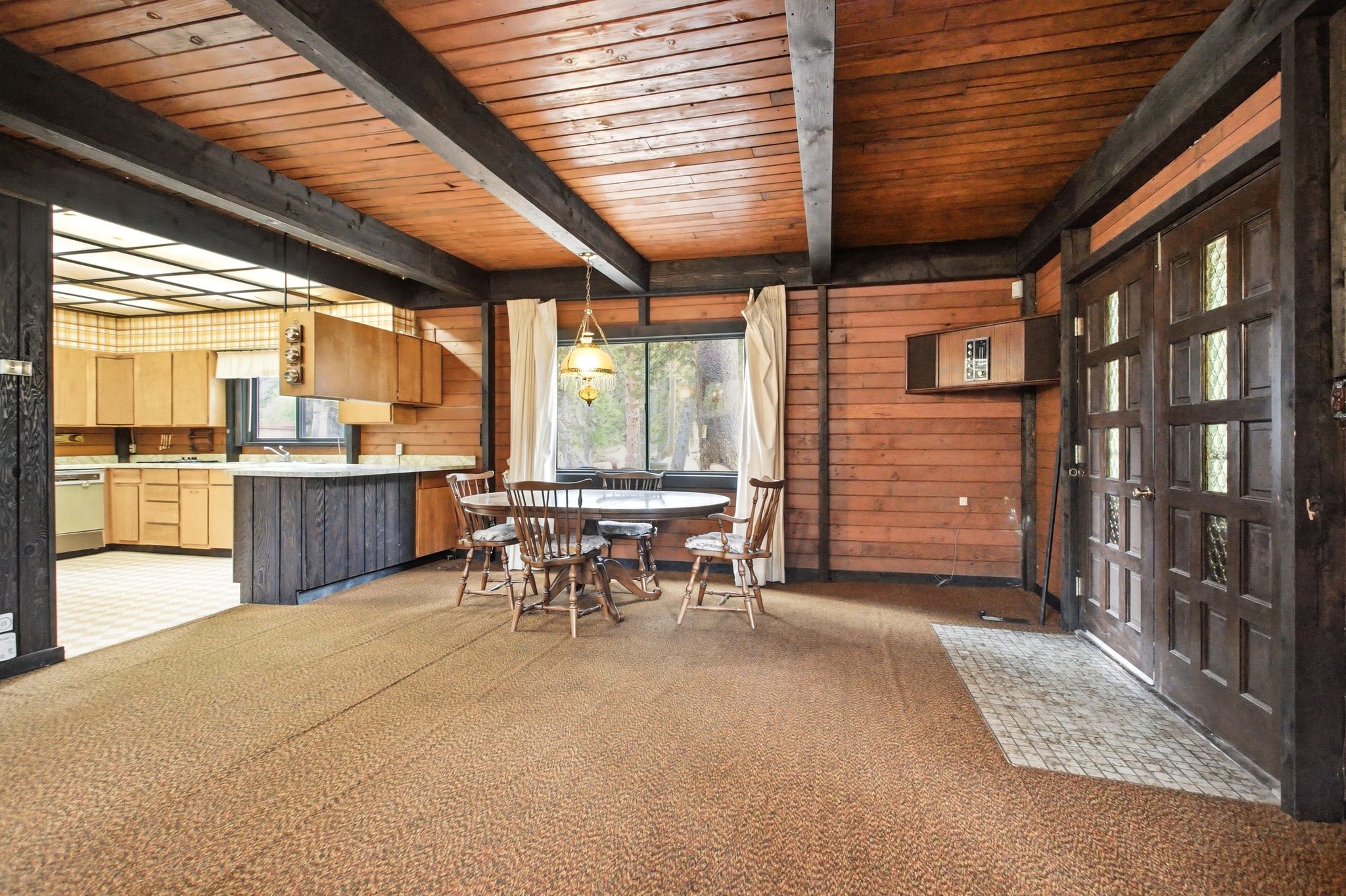 Open-concept living space featuring wood-paneled walls and a wood-beamed ceiling