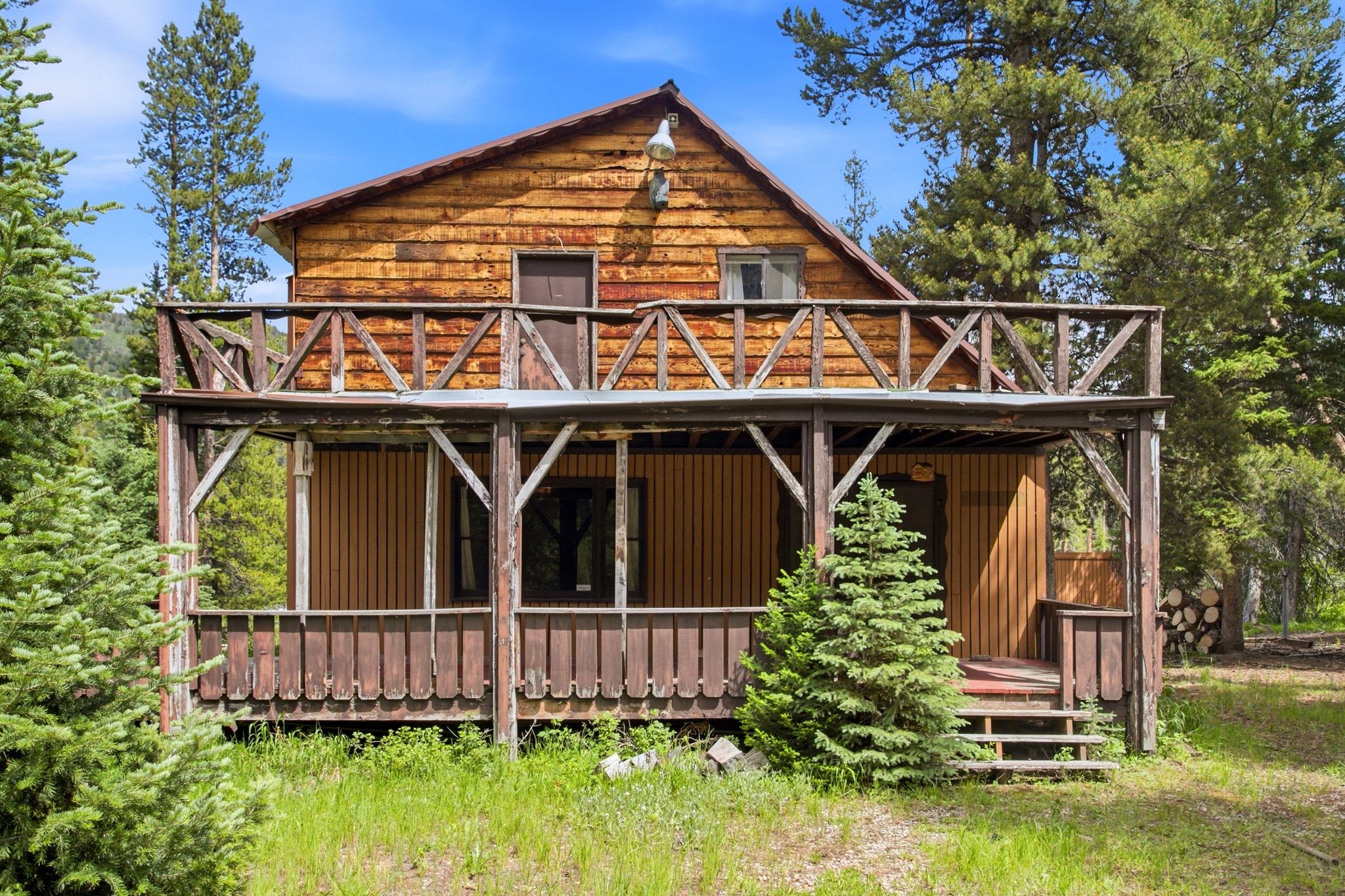 Rustic wood-sided exterior featuring a covered porch, upper balcony, exposed wood rafter tails, and a sloped roofline