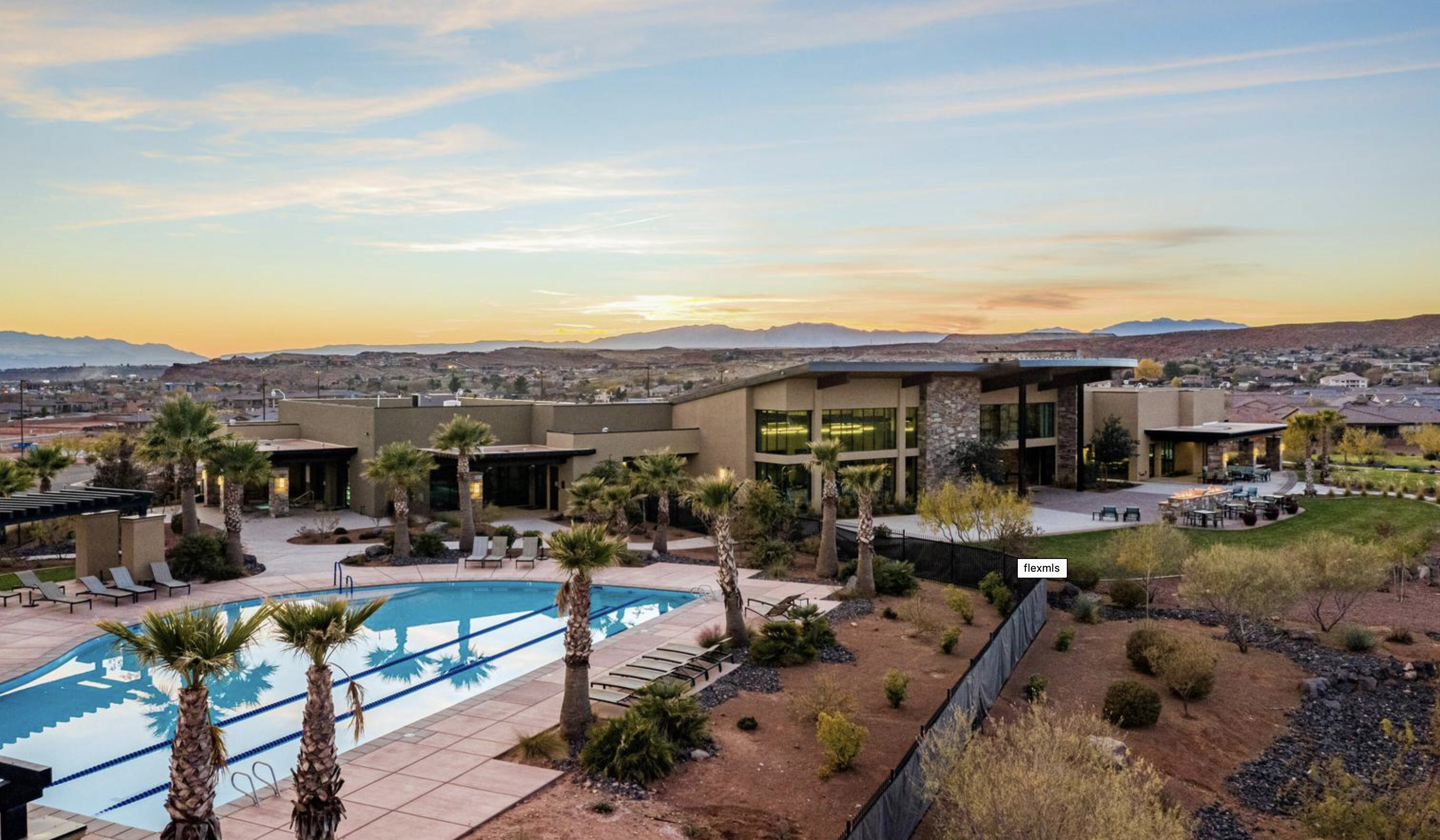 Expansive outdoor pool with integrated lap lanes, surrounded by mature palm trees and ample lounge seating