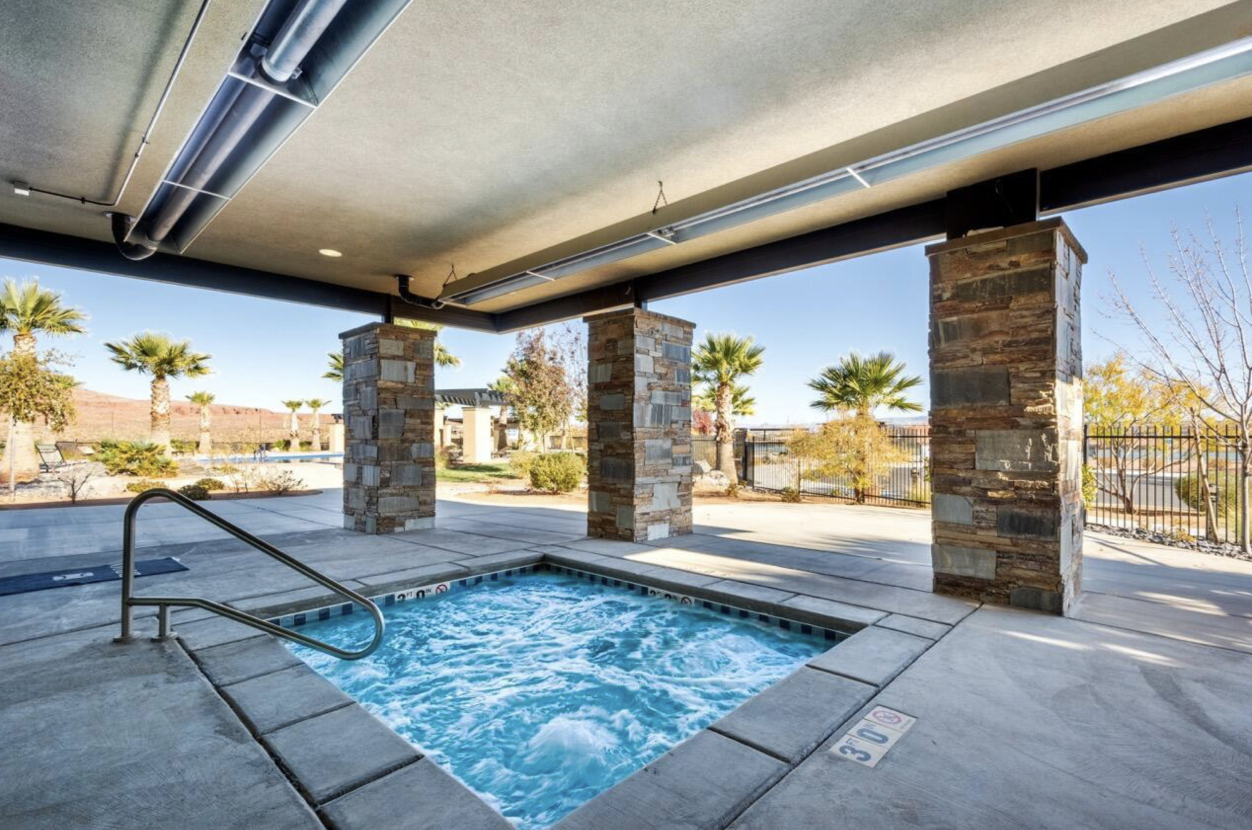 Covered hot tub with concrete surround and a stainless steel grab rail