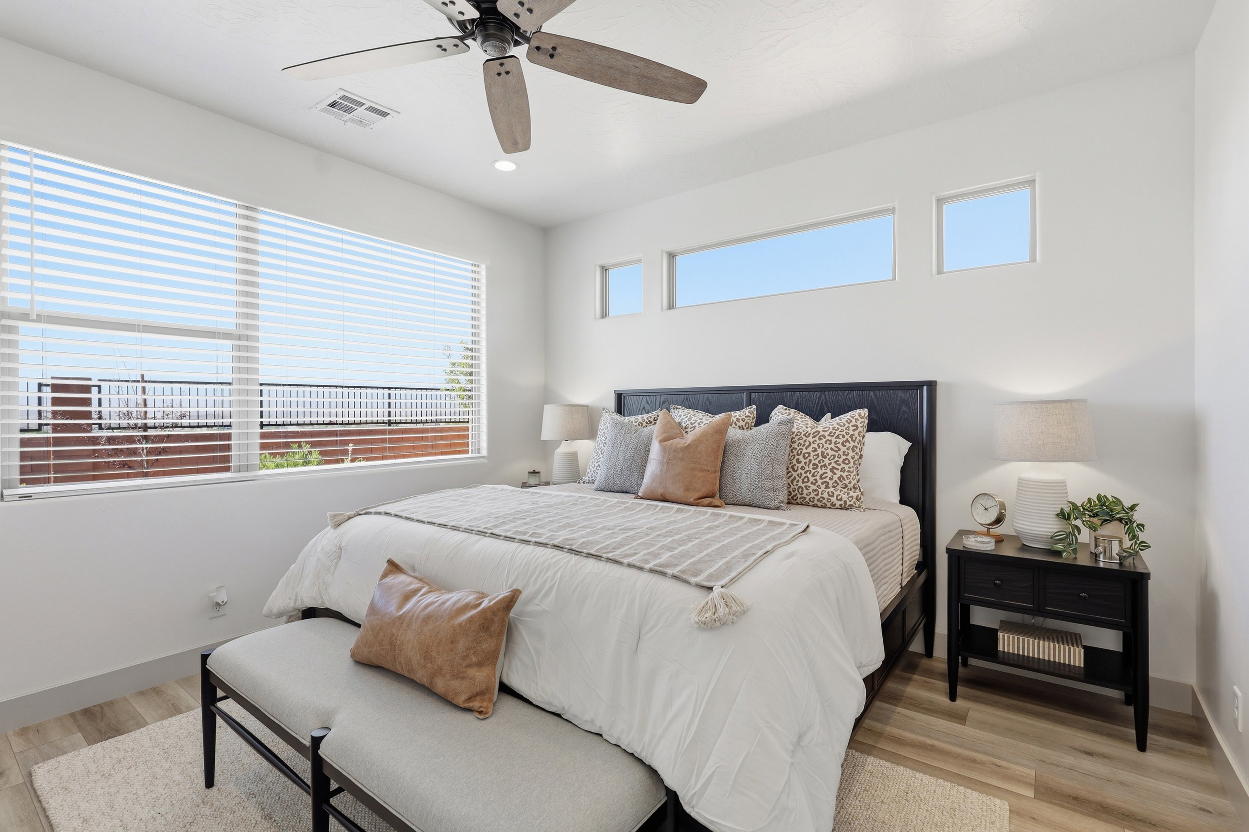 Light wood-finish flooring complements the white walls and ceiling fan