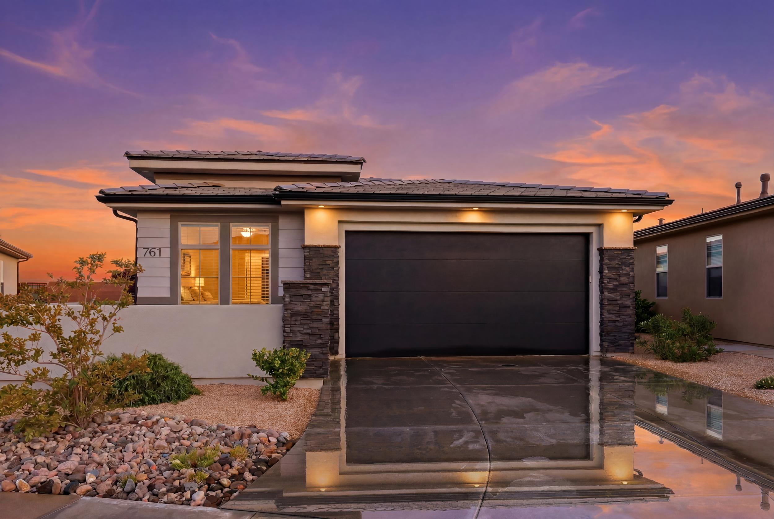 Contemporary exterior featuring a dark garage door, stone accents, and stucco siding