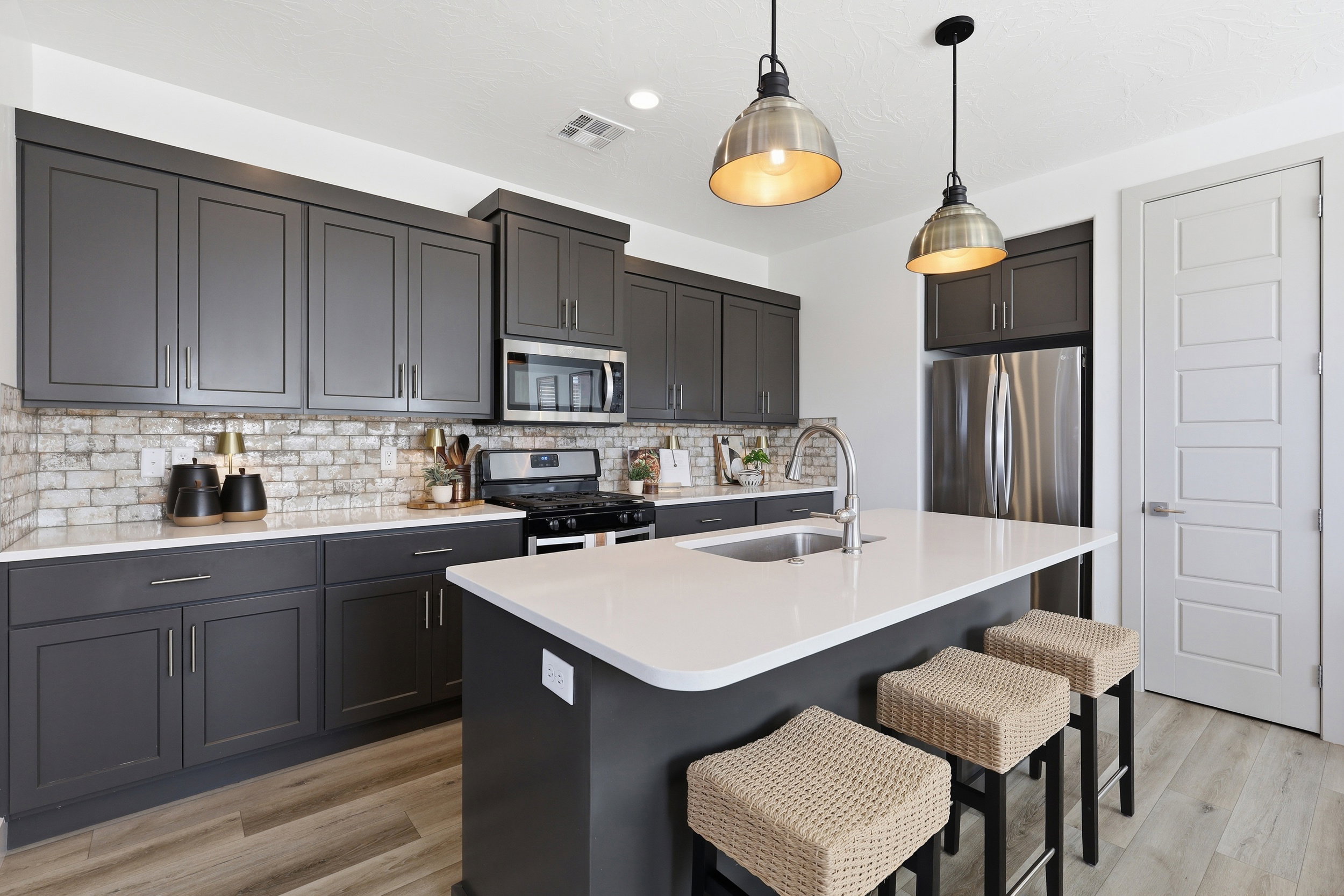 Kitchen featuring dark gray cabinetry, stainless steel appliances, white countertops, and a subway tile backsplash