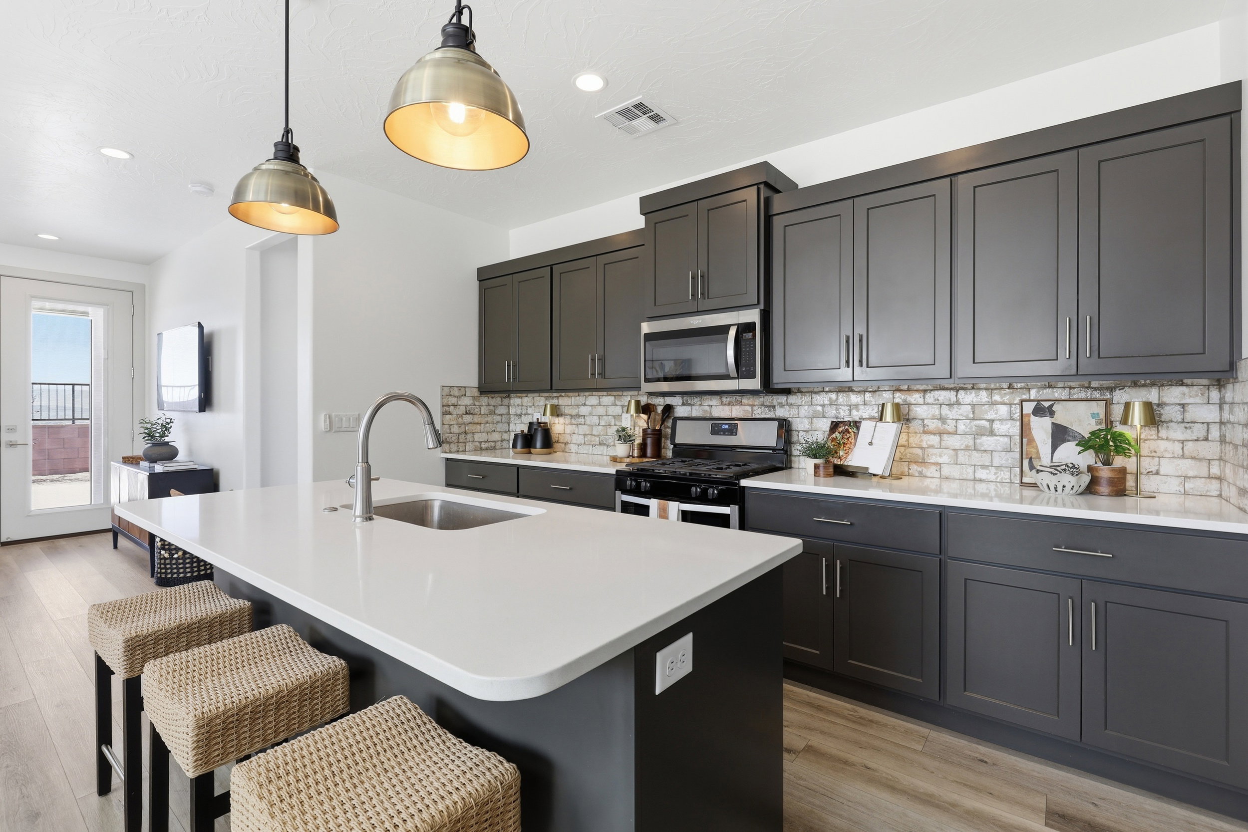 Modern kitchen featuring an island with a stainless steel sink, quartz countertop, and pendant lighting