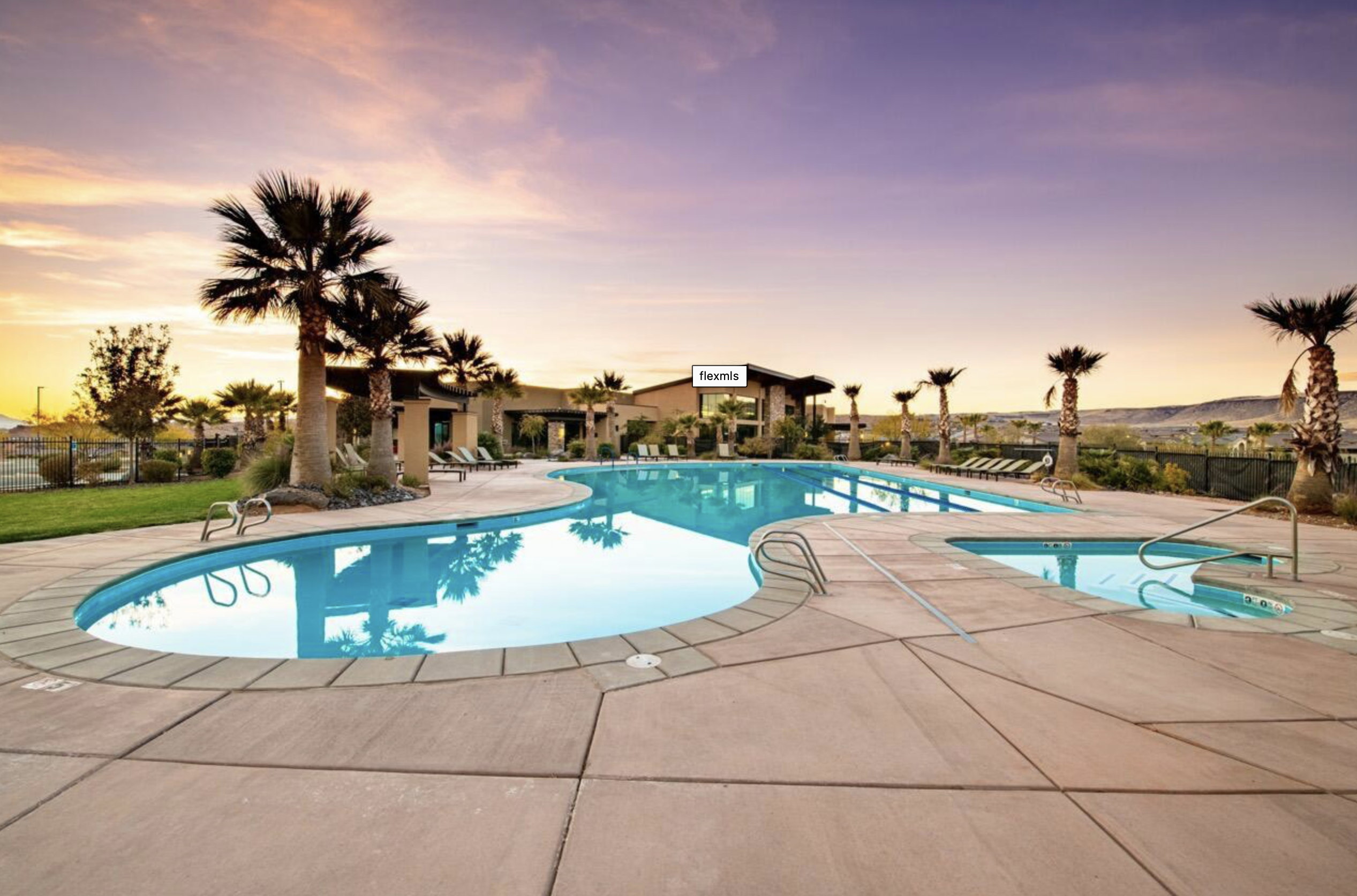 Resort-style pool area featuring a freeform swimming pool, integrated spa, and expansive concrete decking