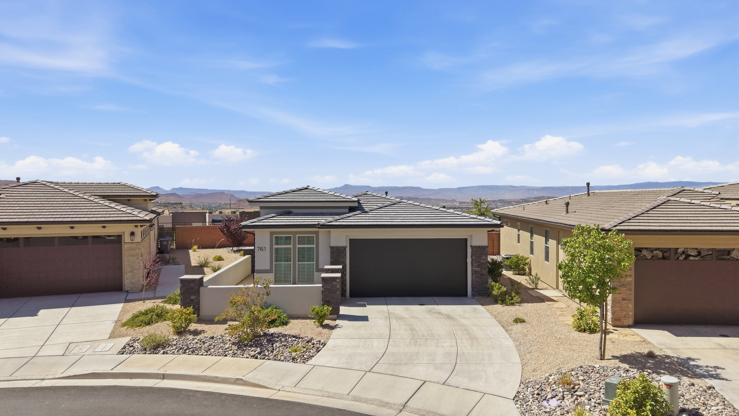 Contemporary desert-style residence with a dark tile roof and integrated garage