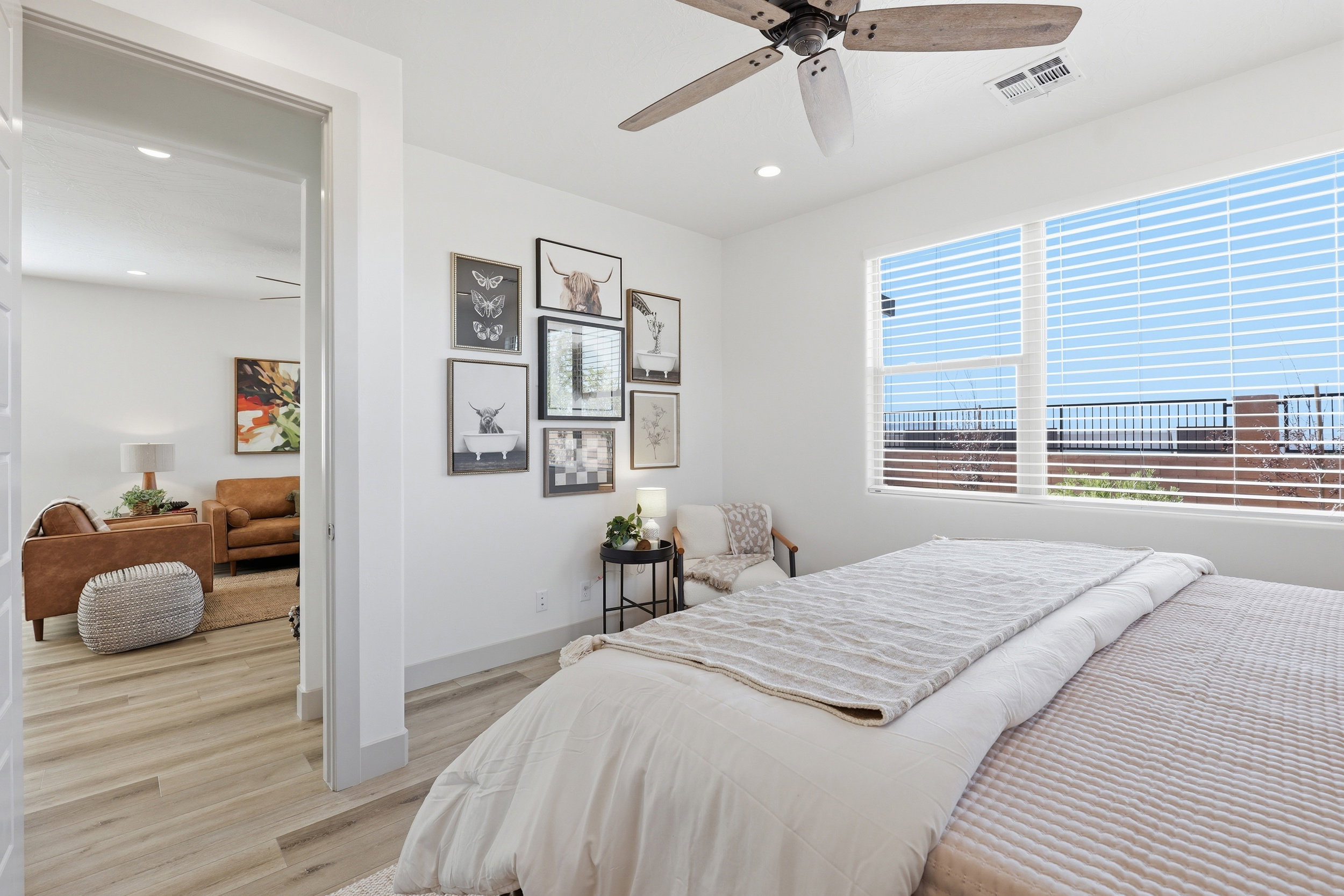 Spacious bedroom with a large window featuring horizontal blinds, a ceiling fan, and wood-finish flooring