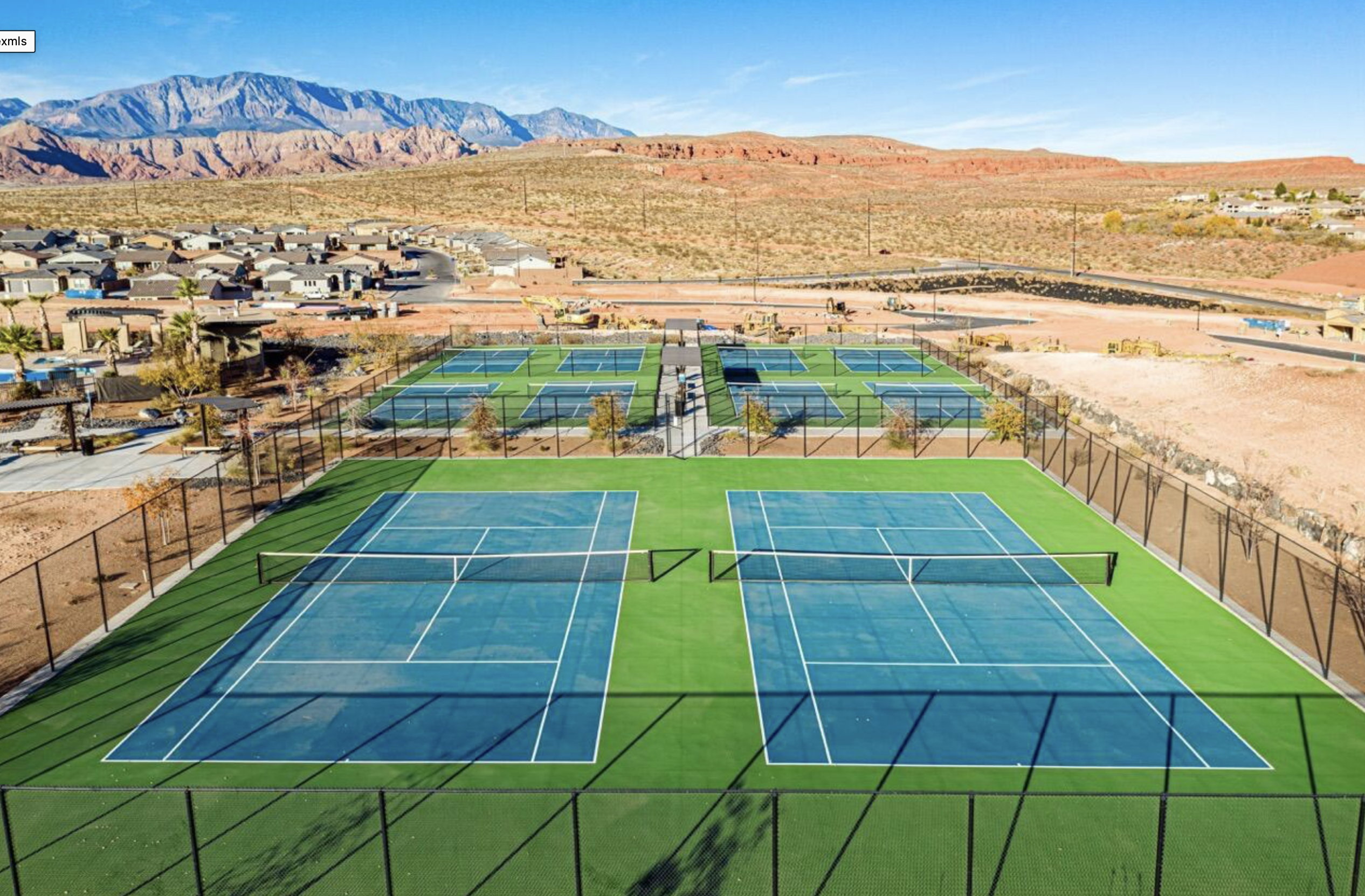 Multiple blue tennis courts with green surrounding turf