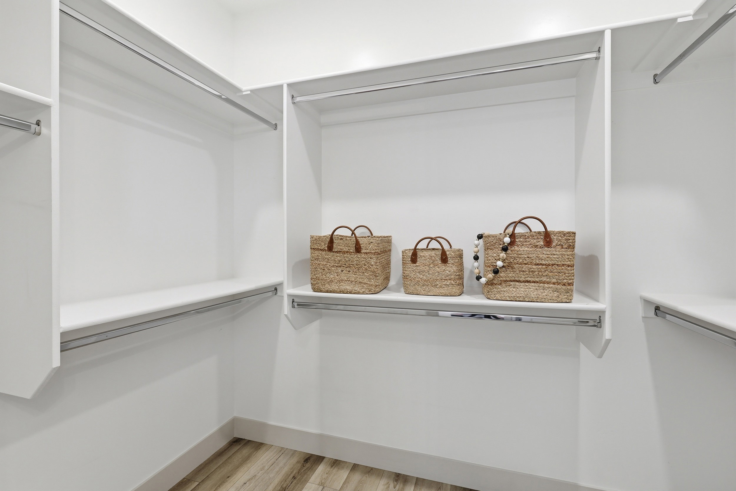 Custom closet system featuring white shelving and chrome hanging rods