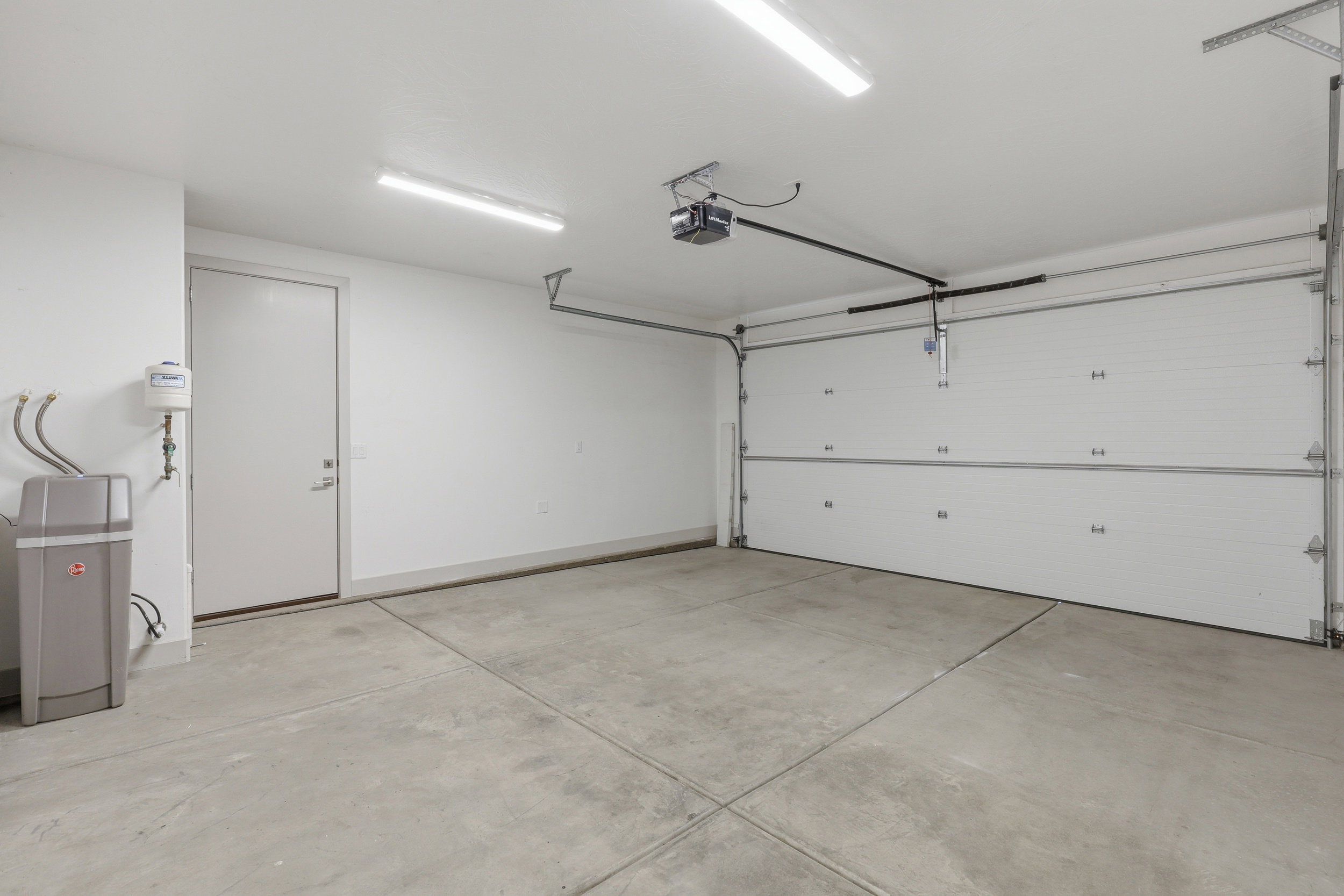 Spacious garage featuring a concrete floor, overhead lighting, and an automatic garage door opener