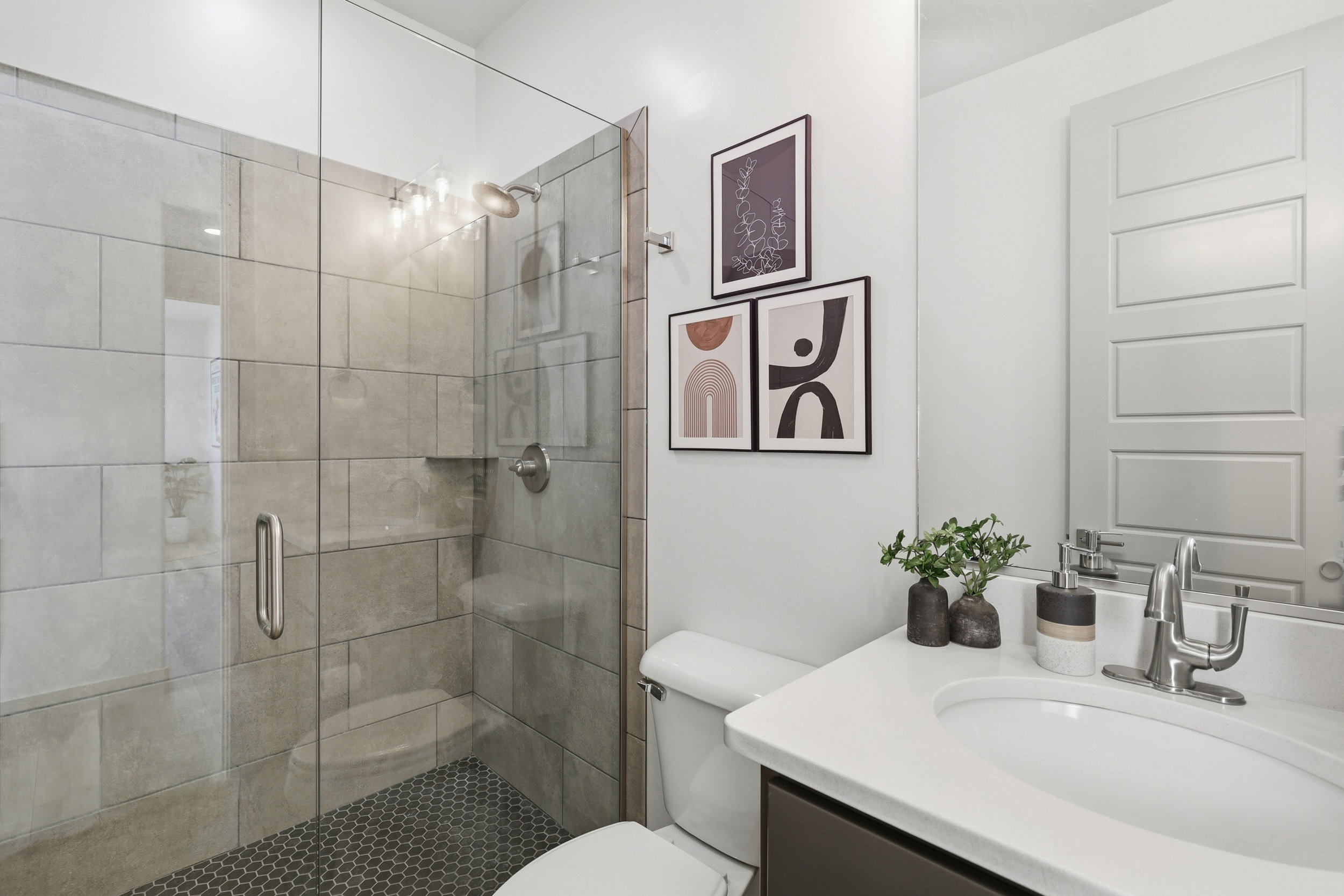 Glass-enclosed shower with rectangular wall tiling and dark hexagonal floor tiles