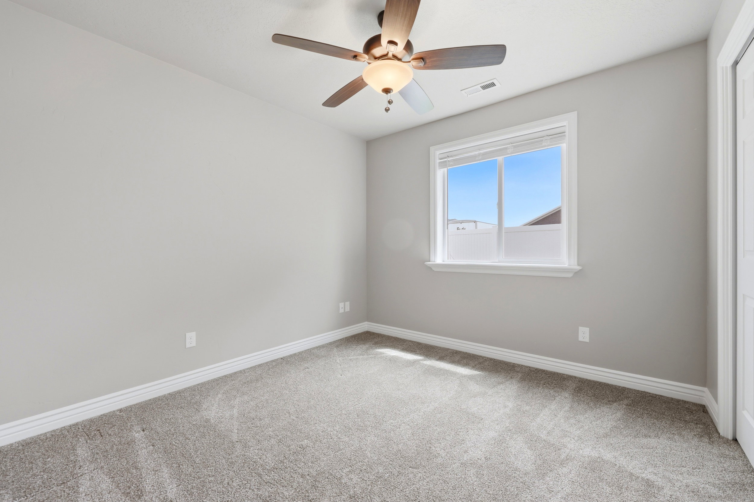 Room featuring a window with white trim, light gray walls, and gray carpet flooring could be office or bdrm