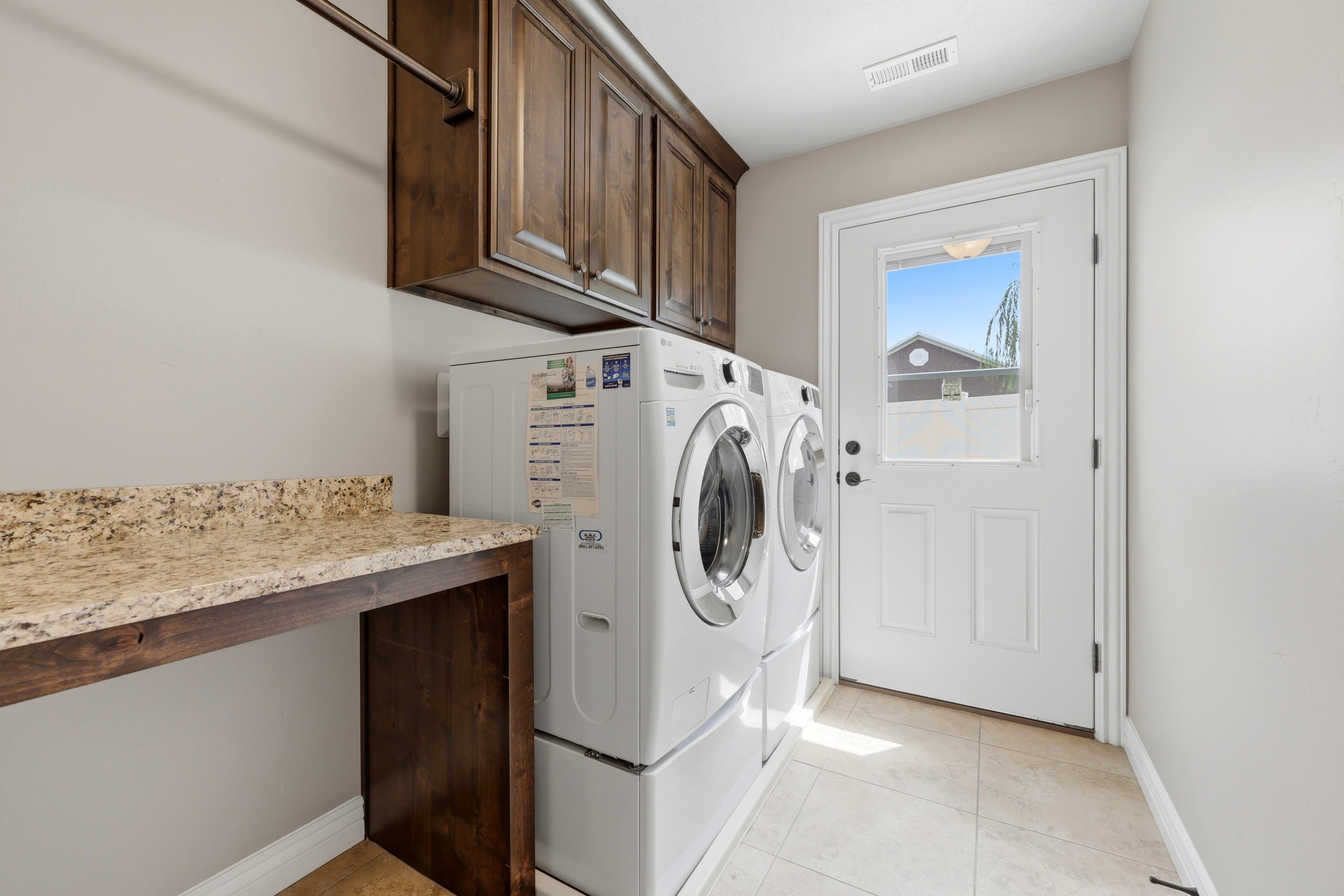Dedicated laundry area featuring a light-toned countertop, wood-finish cabinetry, and a metal hanging rod