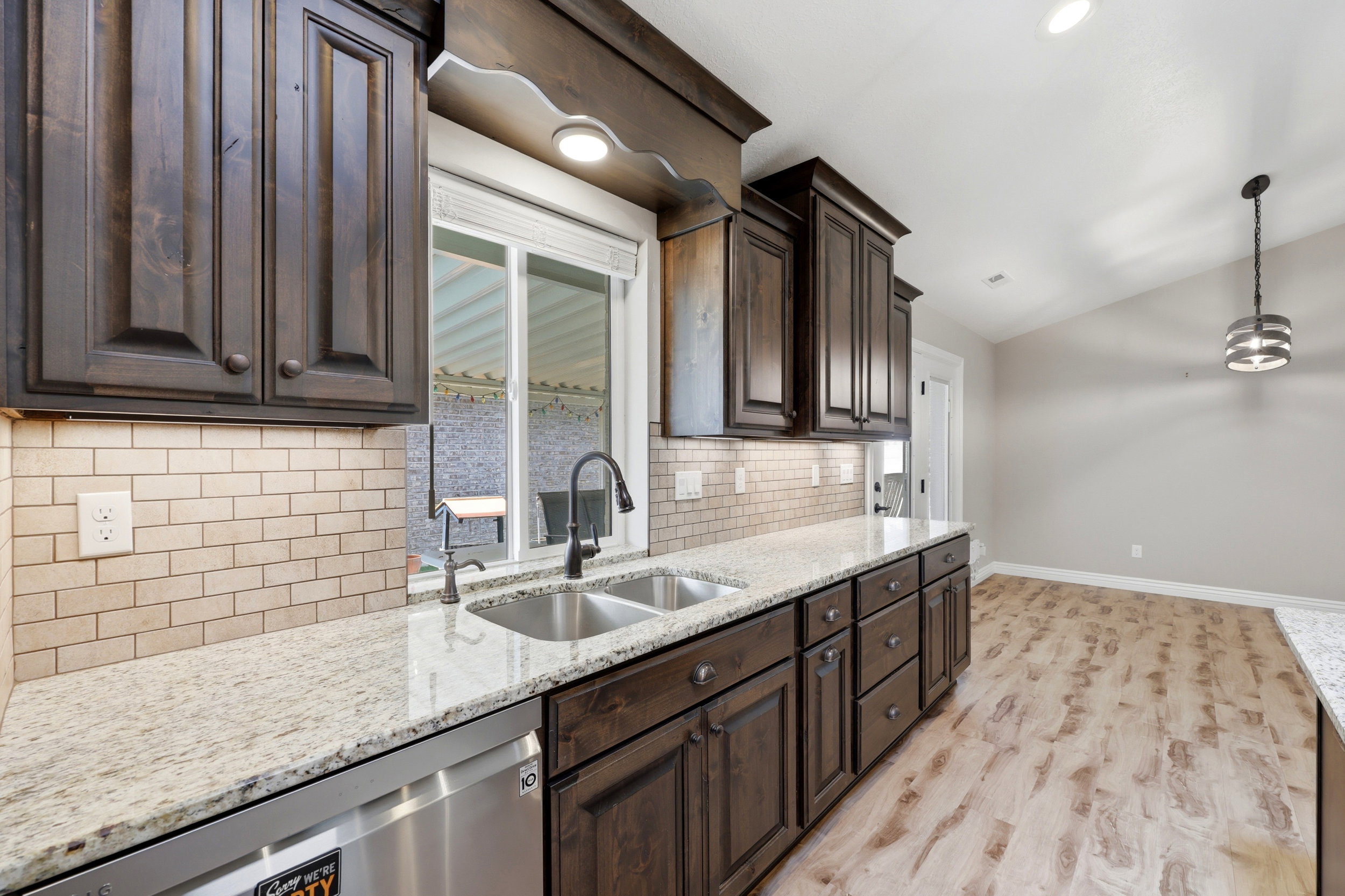 Kitchen featuring dark wood cabinetry, light-toned granite countertops, and a subway tile backsplash