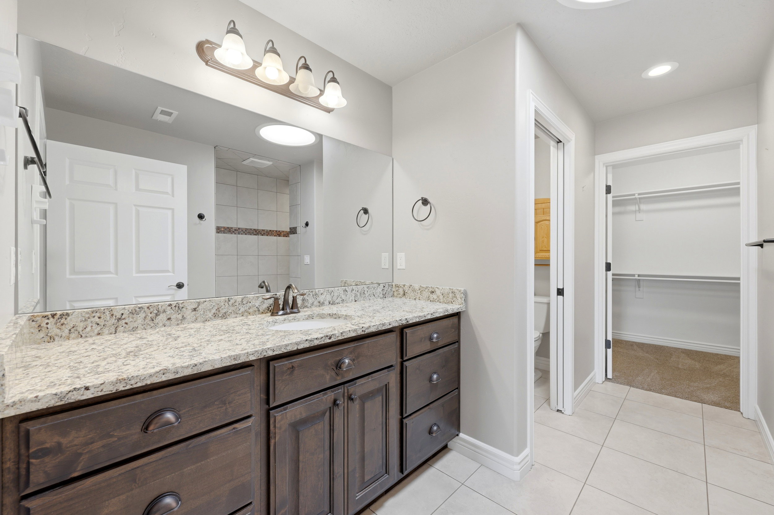 Master bath w/Vanity featuring a stone countertop with an integrated sink, wood-finish cabinetry, and a bronze-finish faucet