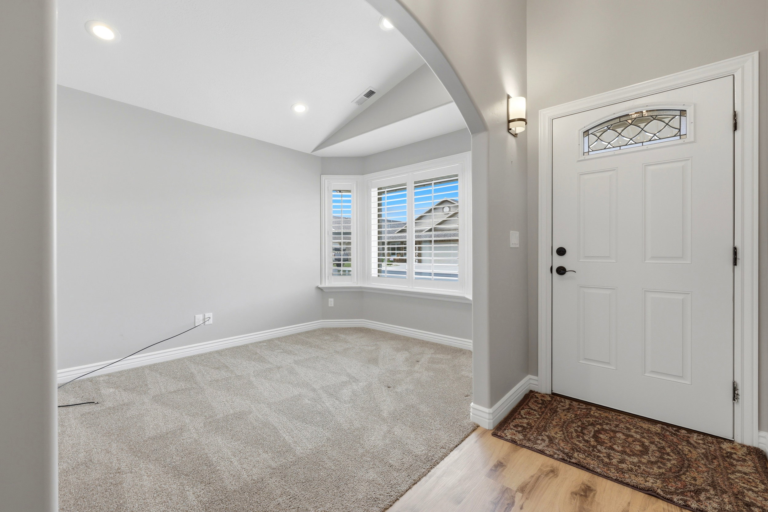 Entryway featuring a decorative front door with an arched transom, a wall sconce, and wood-finish flooring into formal living room