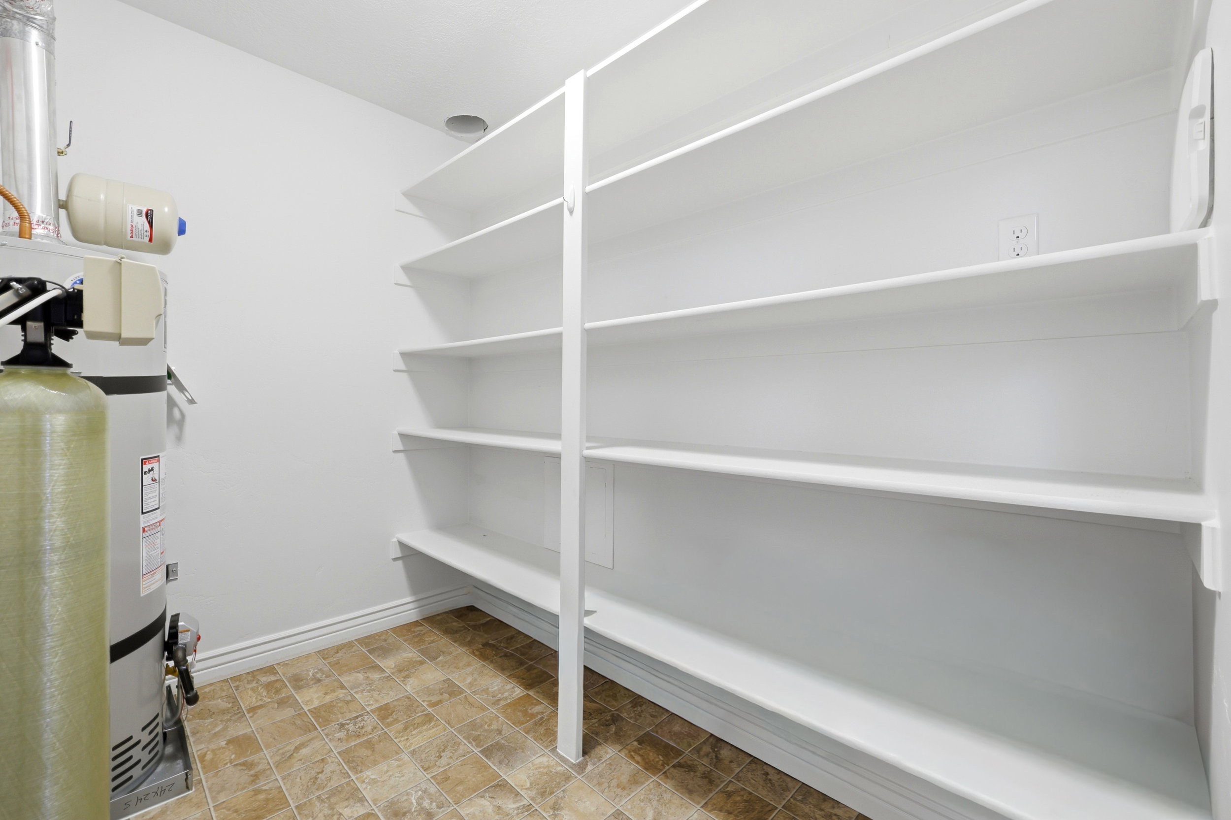 Utility room featuring built-in shelving, durable tile flooring, and white baseboards