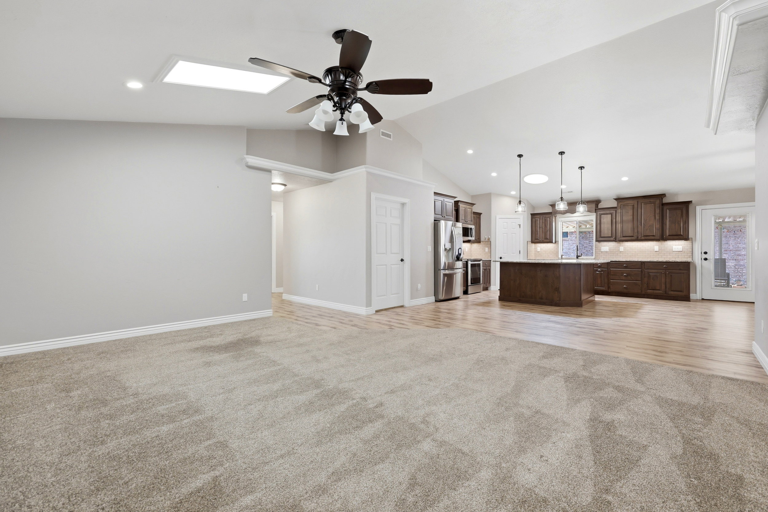 Expansive open-concept room featuring vaulted ceilings, a skylight, and a ceiling fan