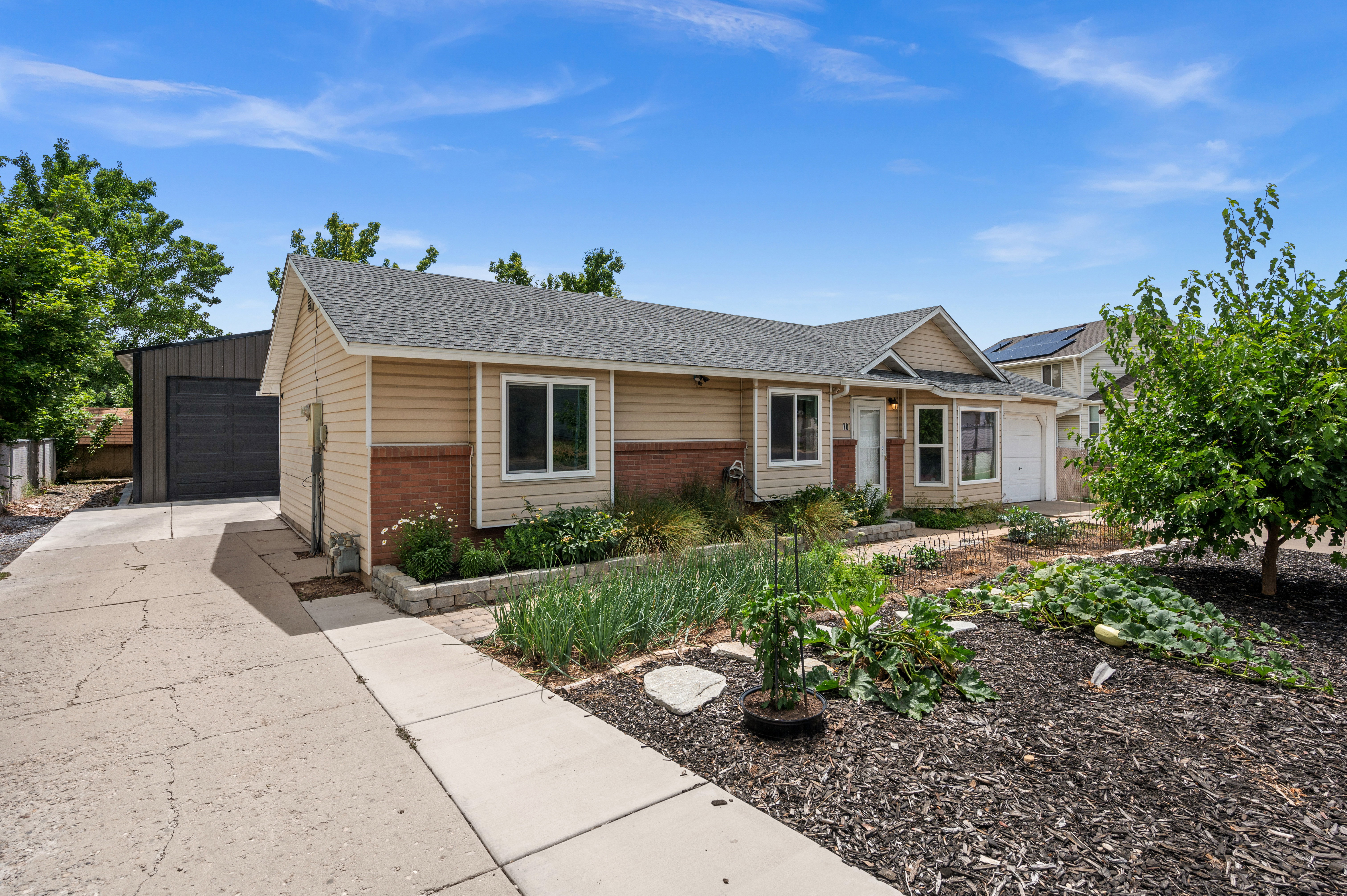 Exterior featuring light-colored siding, brick accents, a gabled roofline, and an attached garage