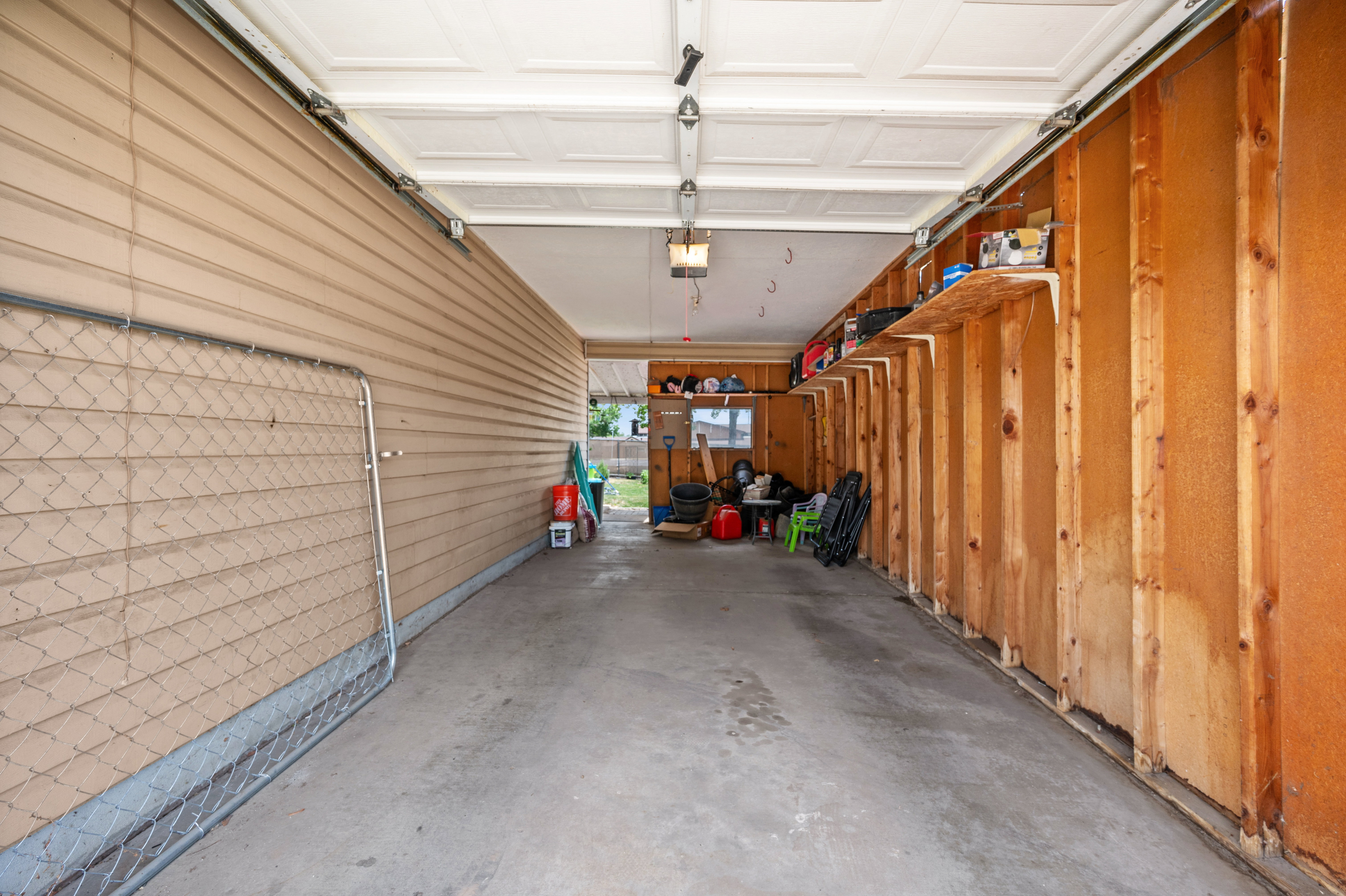 Attached garage with a concrete floor, built-in shelving, and exposed wood framing