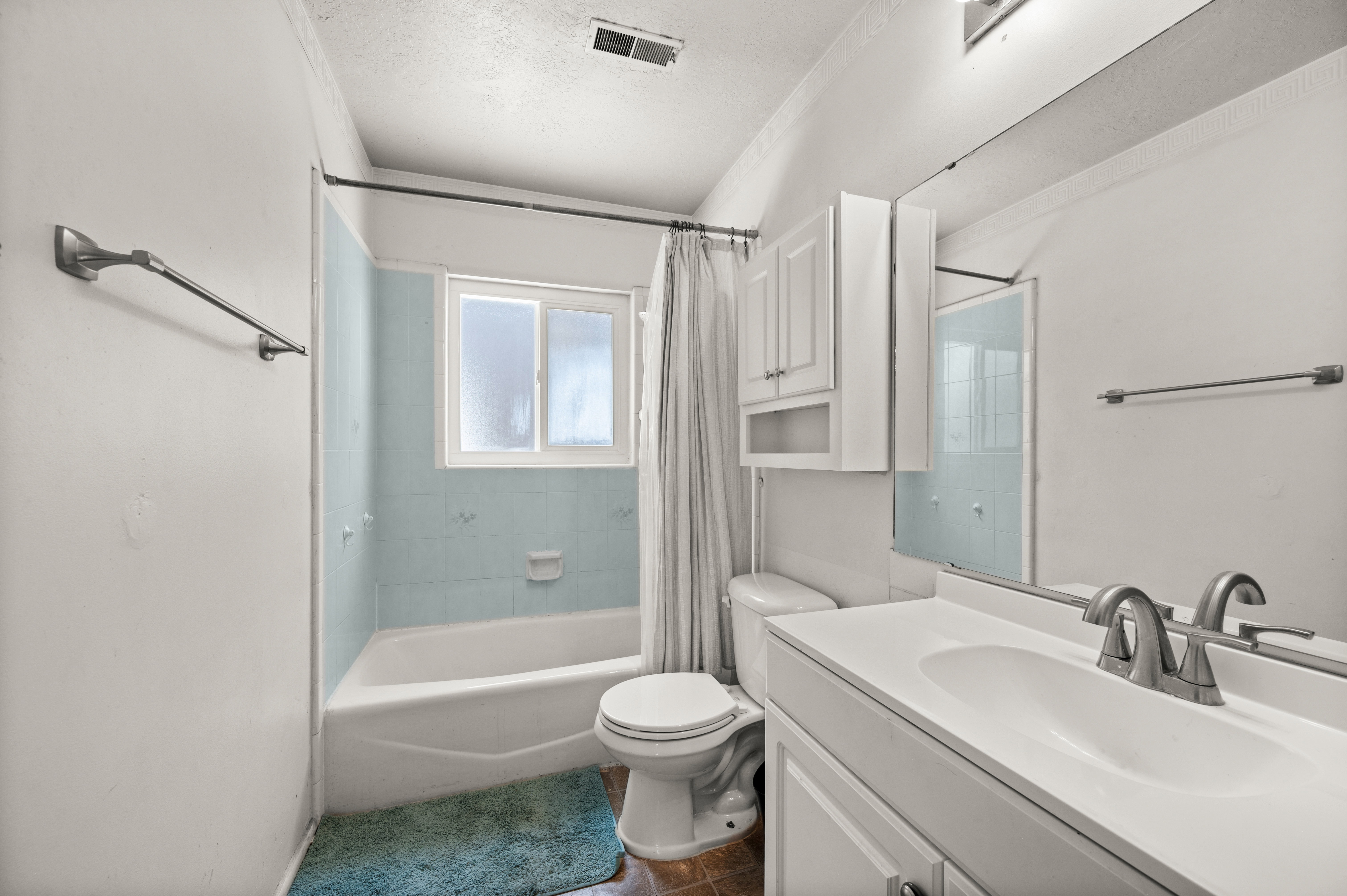 Bathroom featuring a single vanity with an integrated sink, brushed nickel faucet, and a large wall mirror