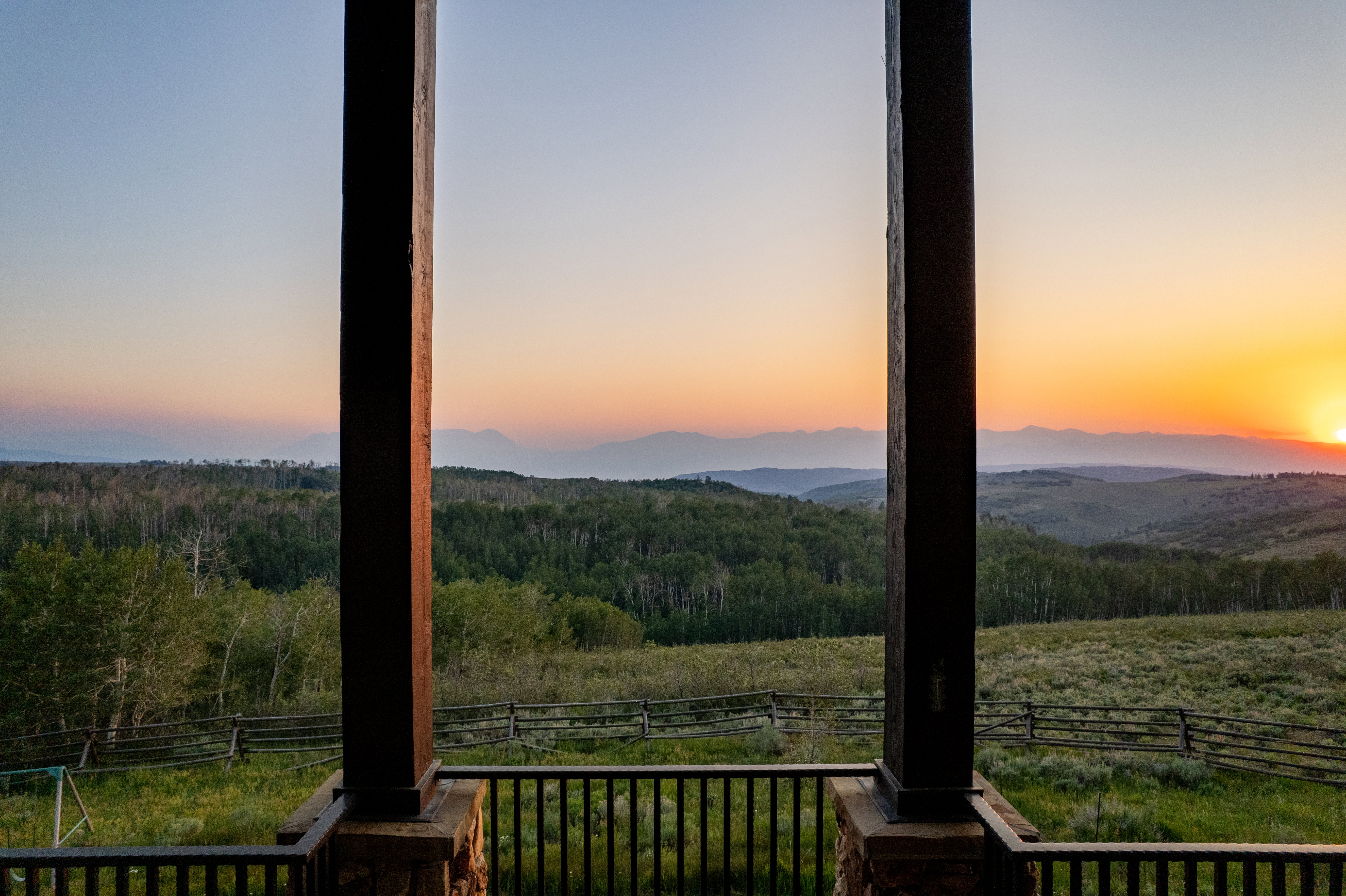 Expansive mountain and forest scenery observed from a covered outdoor living space