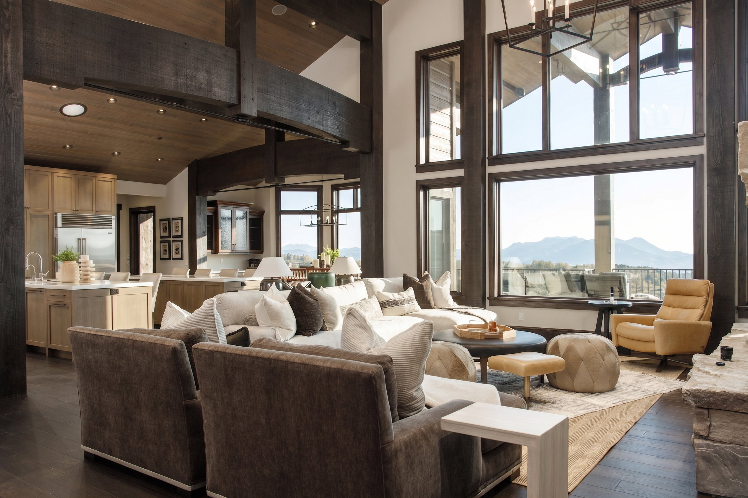 Great room featuring soaring ceilings with exposed dark wood beams, expansive windows, wood-finish flooring, and a stone-clad fireplace