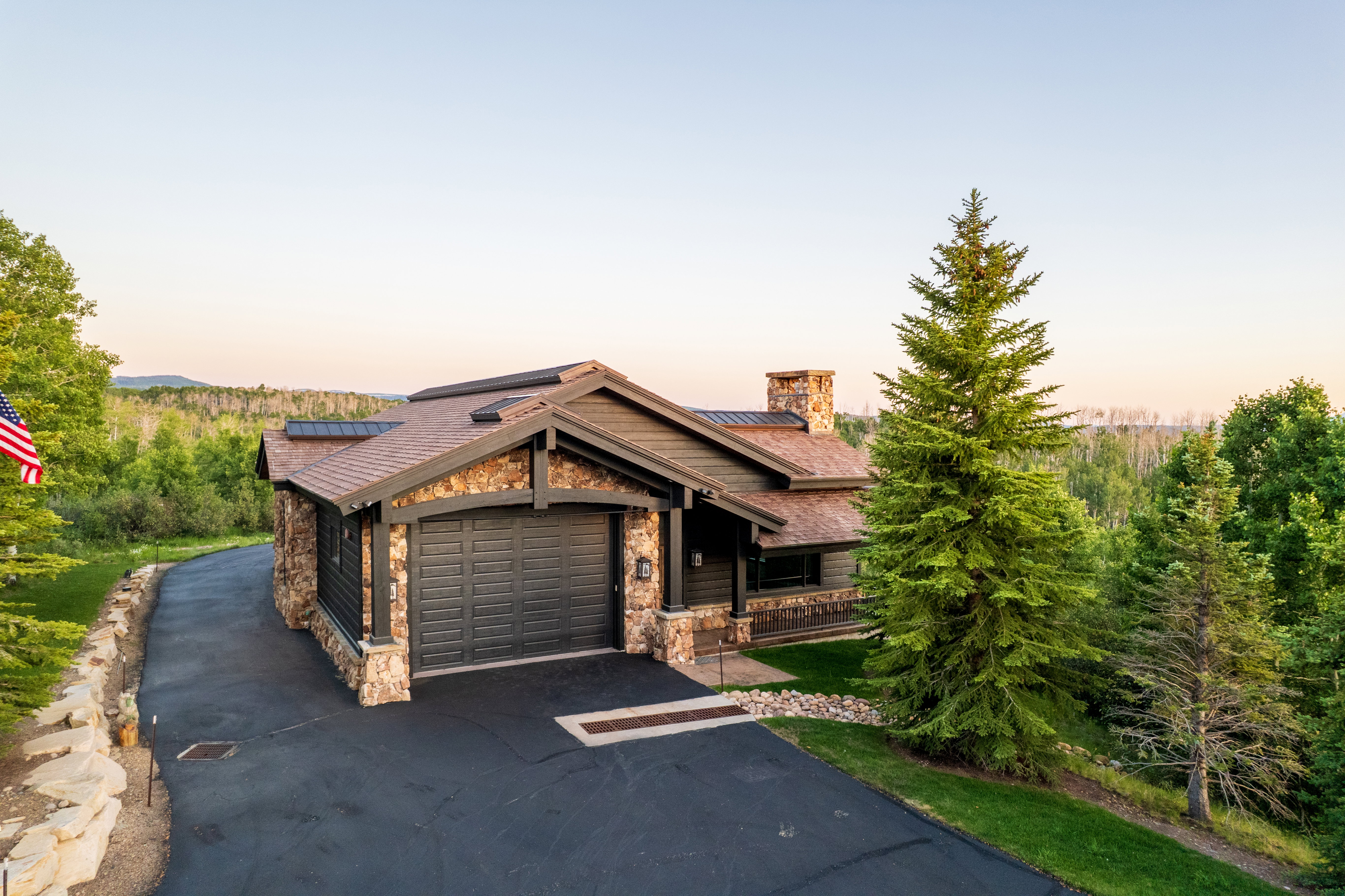 Craftsman-style home featuring a stone and wood exterior with a dark asphalt driveway