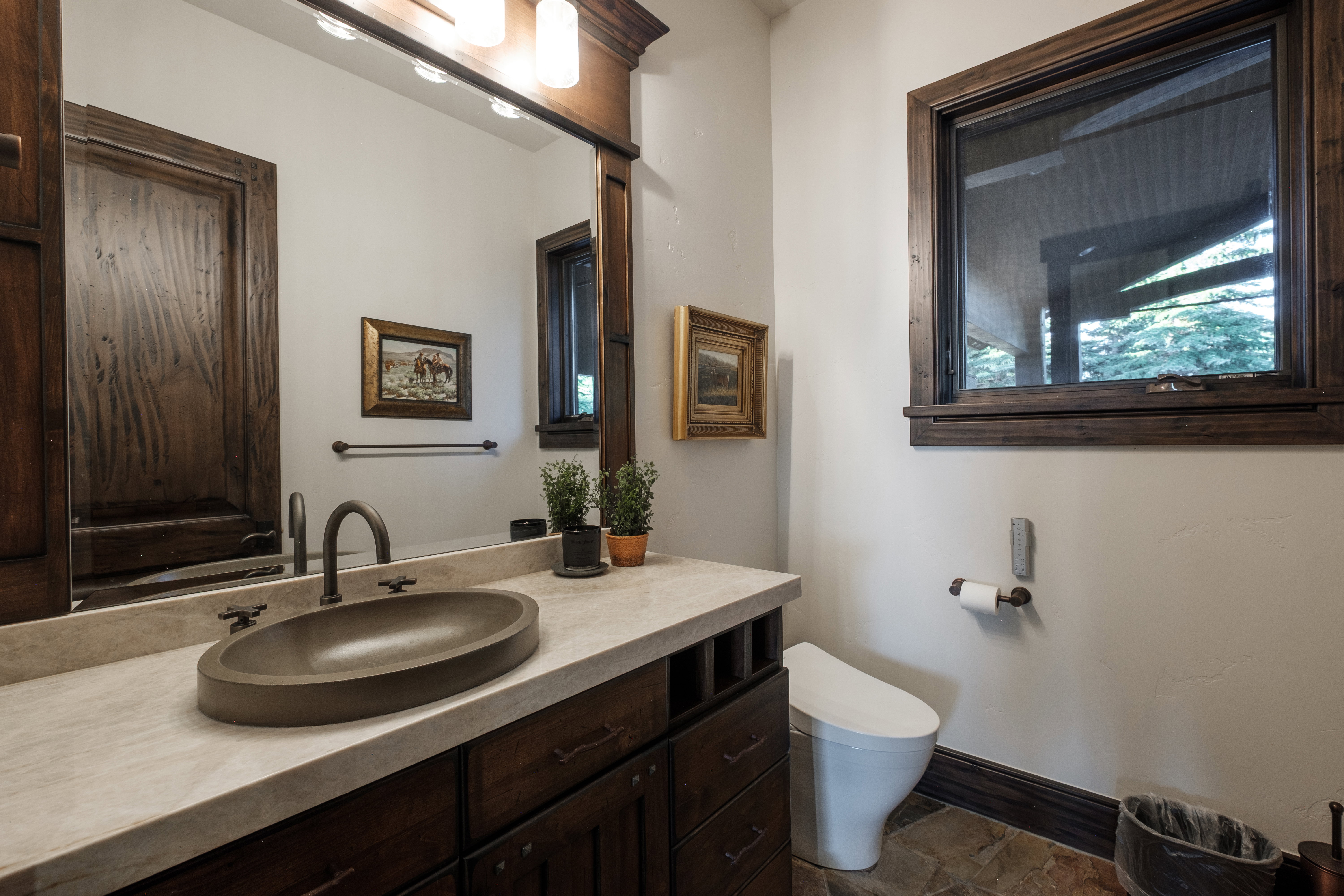 Bathroom featuring a dark wood vanity with a light-toned countertop, an oval vessel sink, and a dark bronze faucet