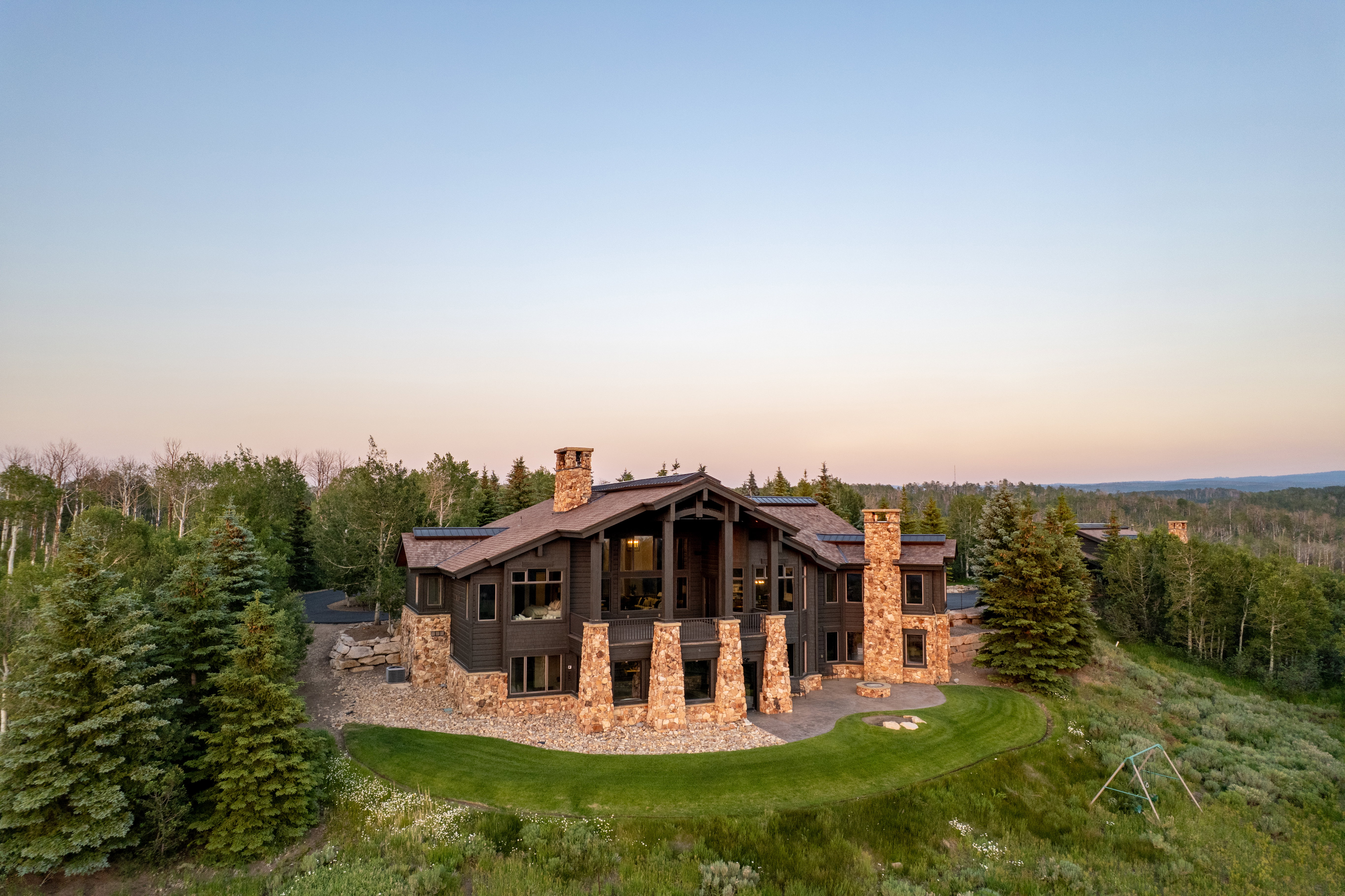 Expansive mountain-style residence featuring a prominent stone and wood exterior