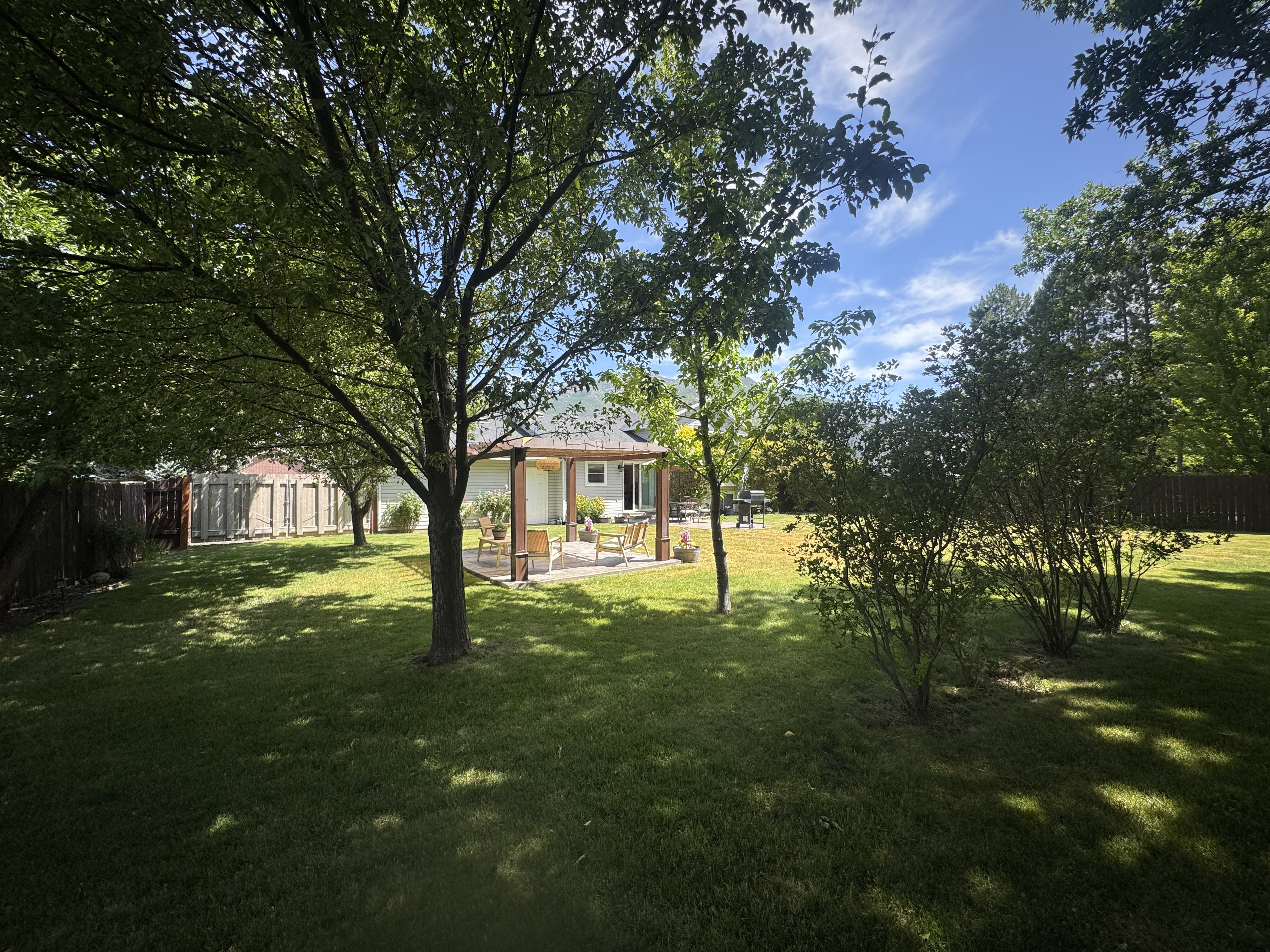 Expansive backyard featuring a lush lawn, mature trees, and privacy fencing