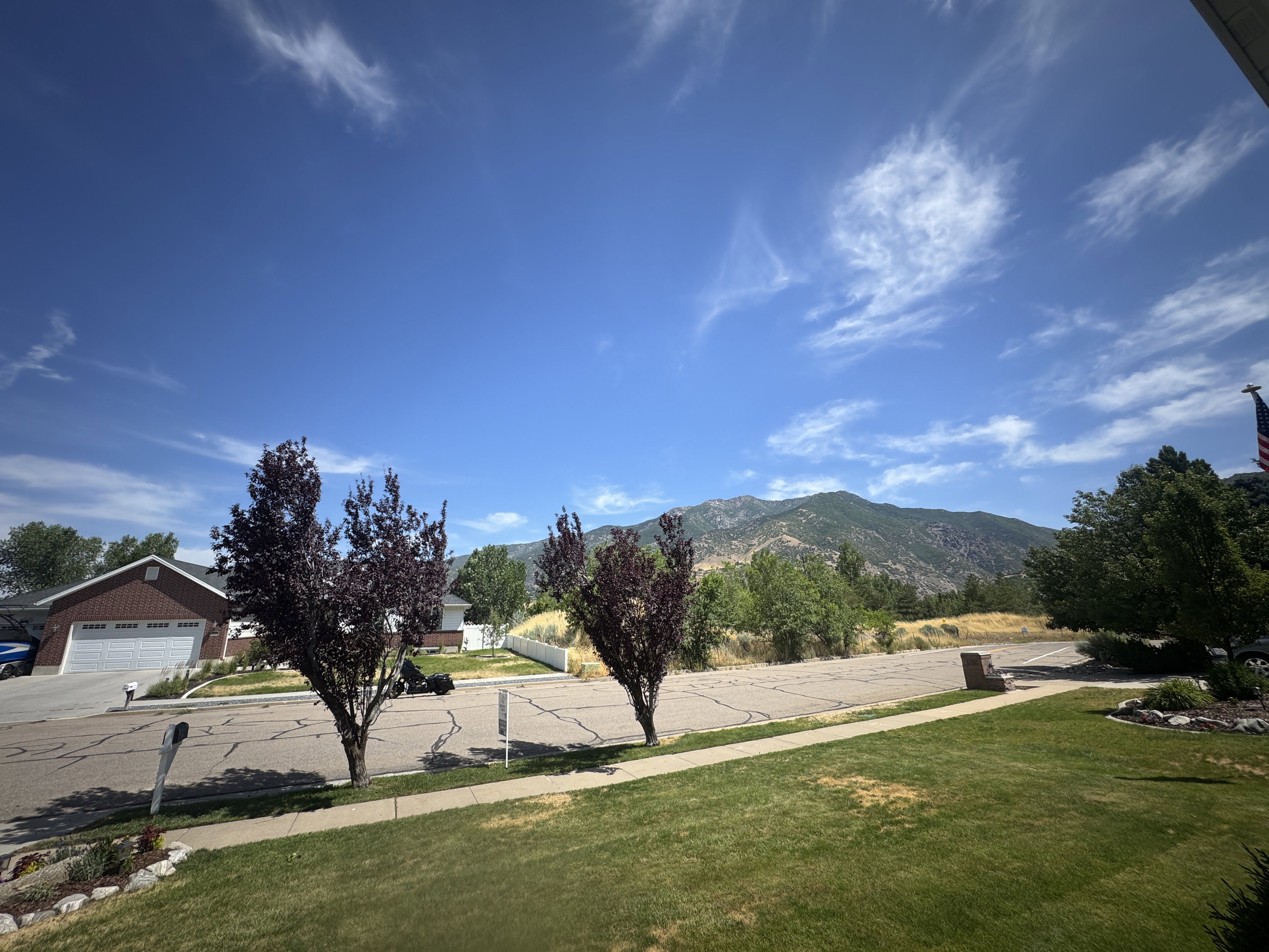 Mountain backdrop with established trees and a manicured lawn
