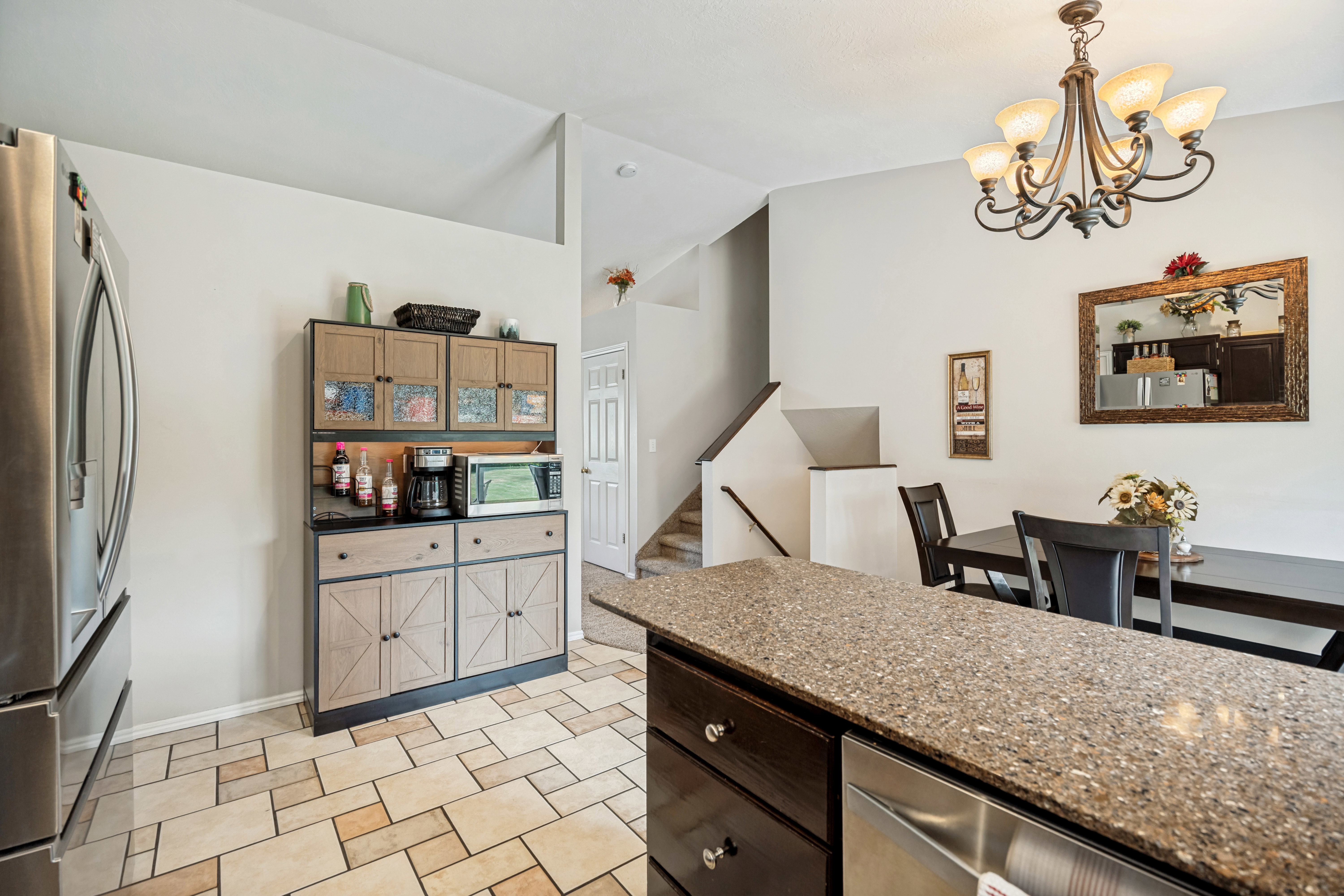 Kitchen area featuring a built-in hutch with upper glass-front cabinetry, a stainless steel refrigerator, and tiled flooring