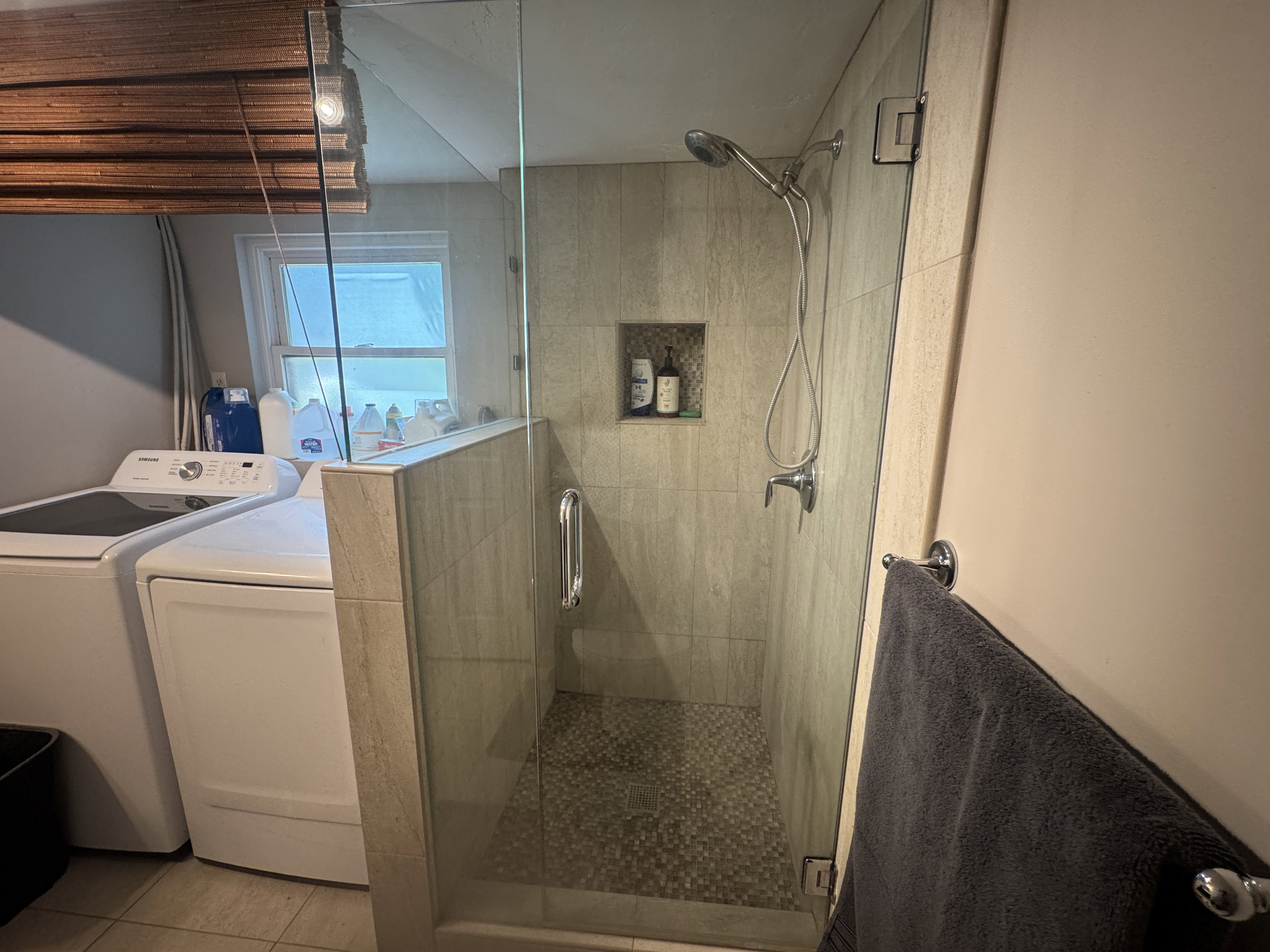 Glass-enclosed shower featuring tiled walls and a pebble-finish floor