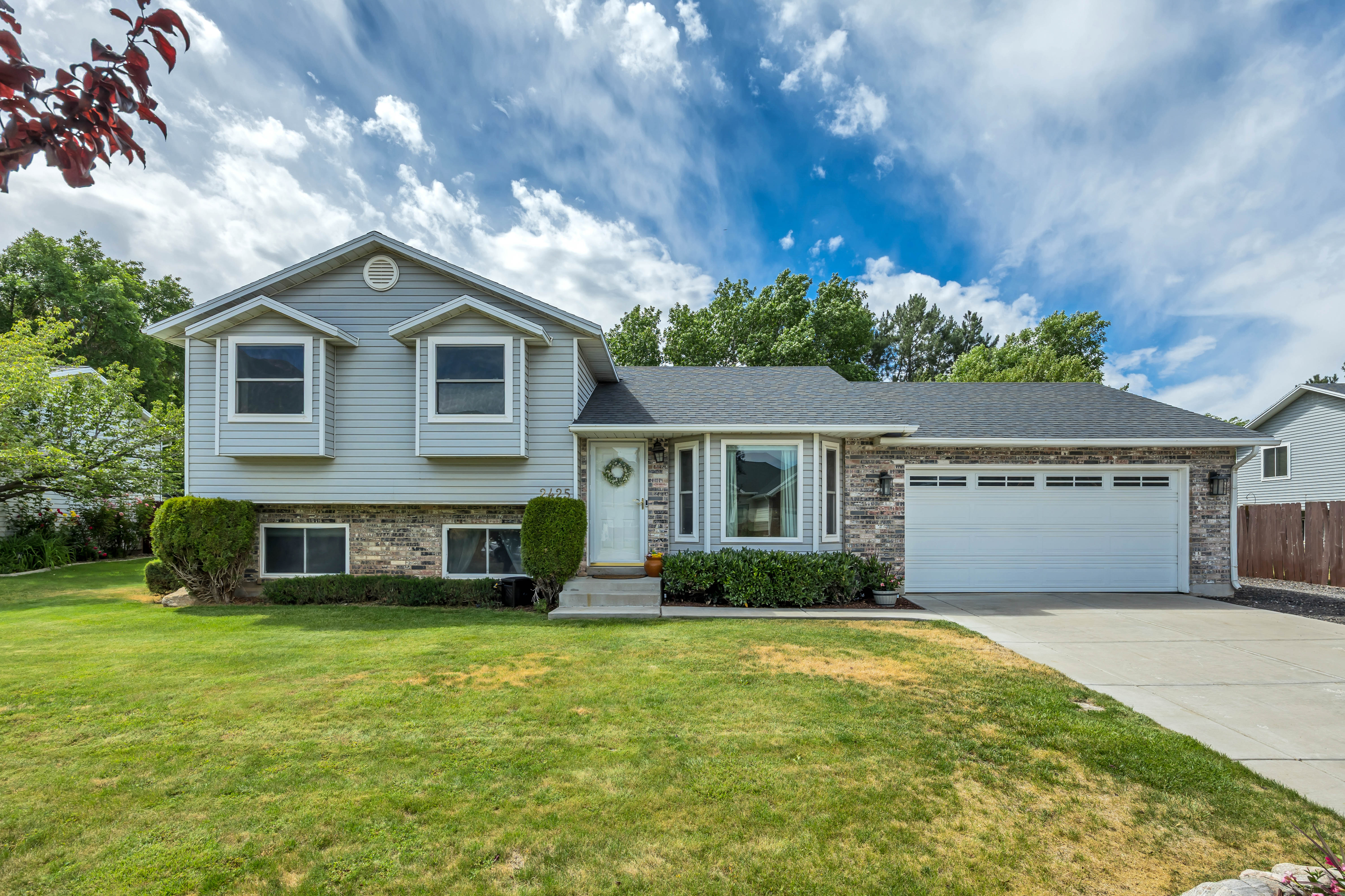 Split-level exterior featuring light blue siding, stone brick accents, and a dark shingle roof