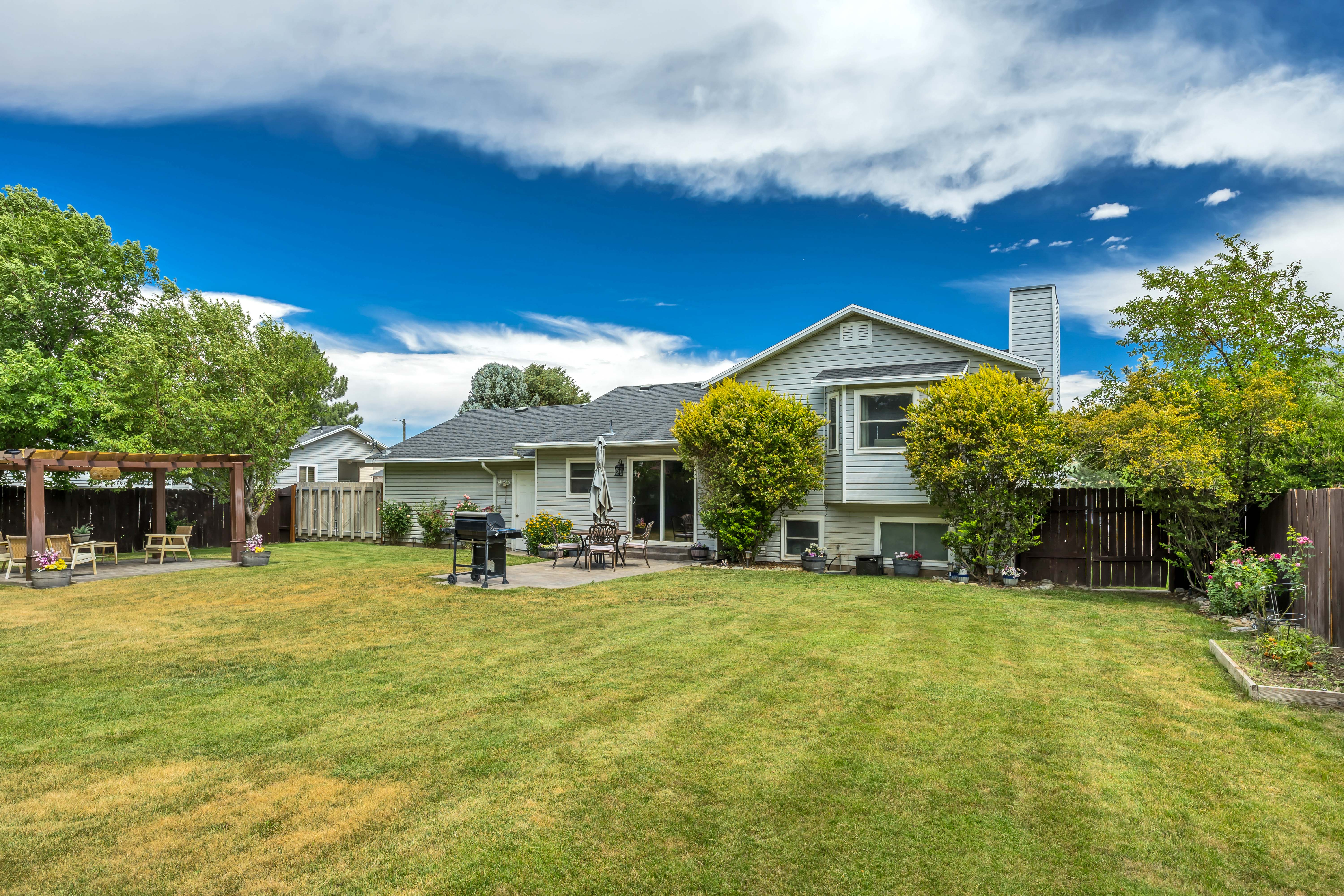 Expansive backyard featuring a large lawn area, a paved patio, and a separate pergola-covered patio
