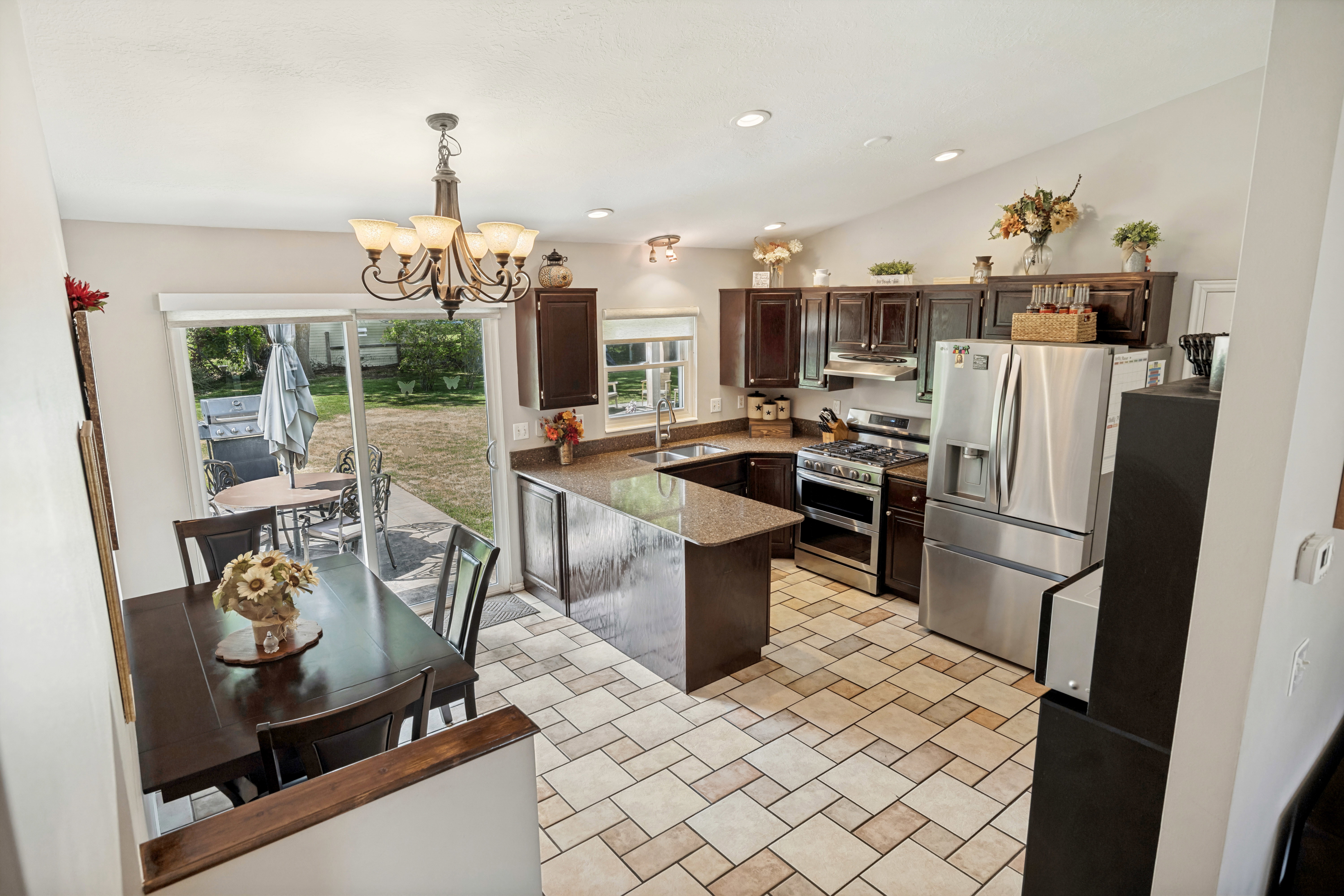 Spacious kitchen and dining area featuring ceramic tile flooring, dark wood cabinetry, and stainless steel appliances