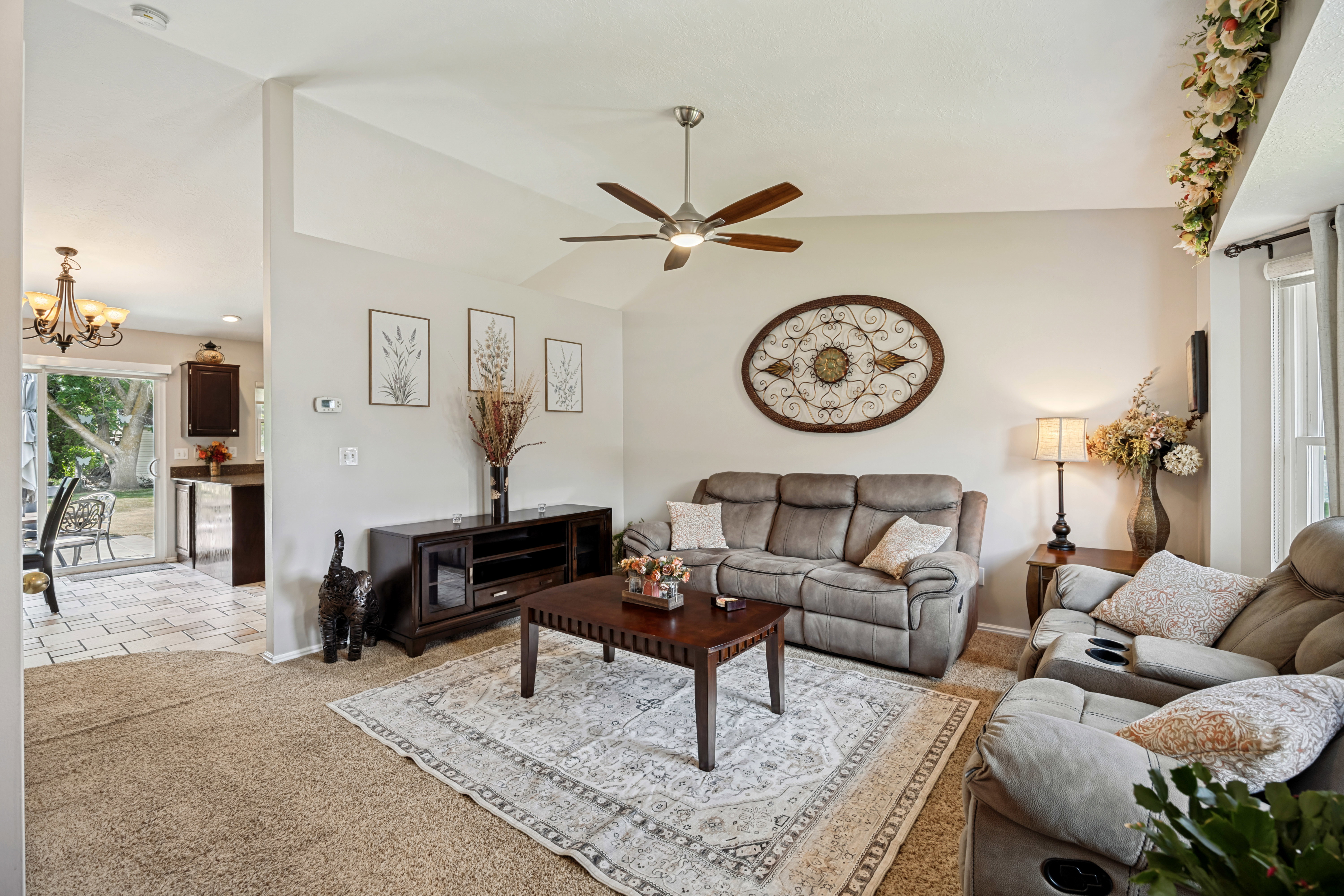 Vaulted ceiling living area featuring a ceiling fan with integrated lighting