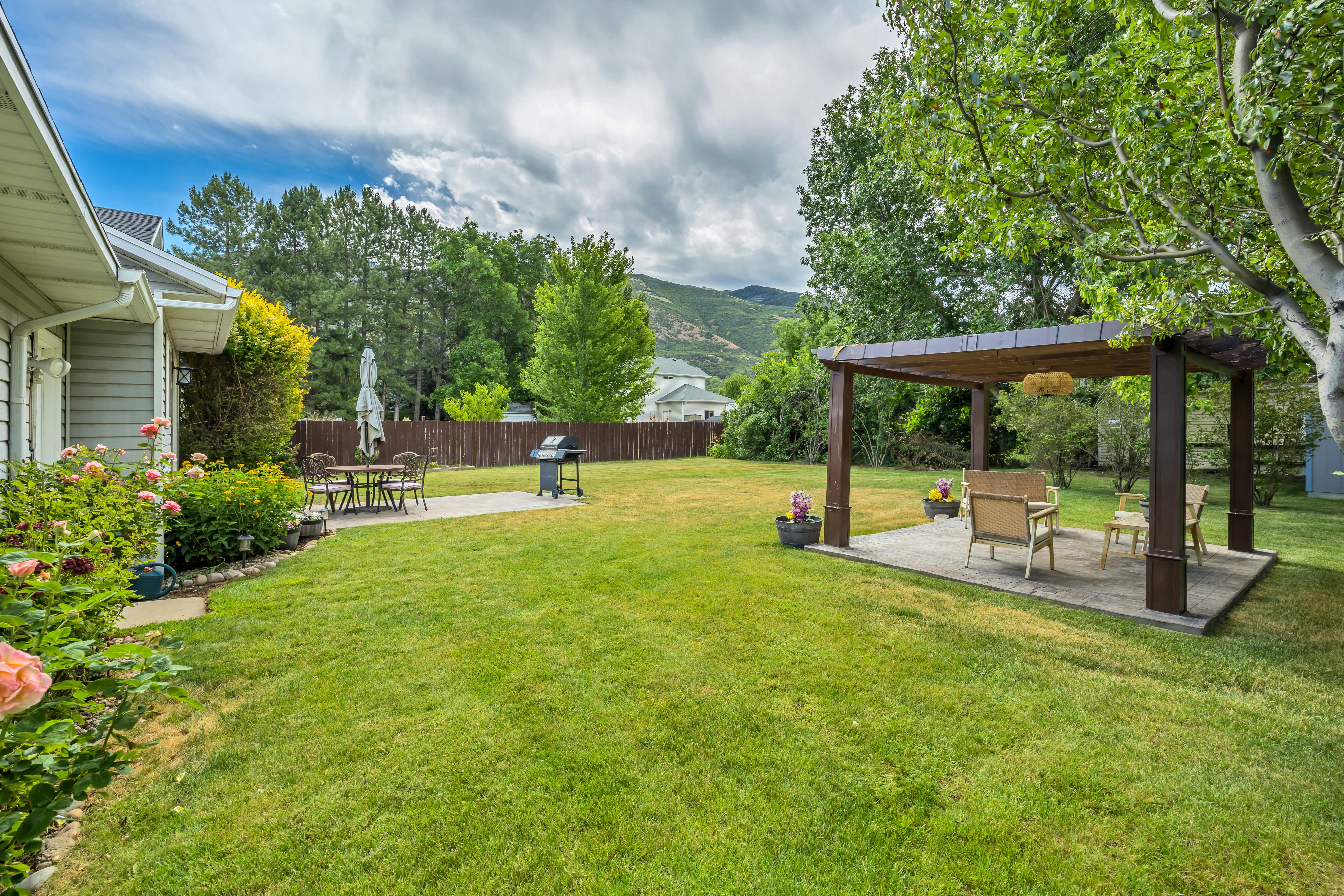 Expansive backyard featuring a large green lawn, a dedicated patio area, and a pergola.