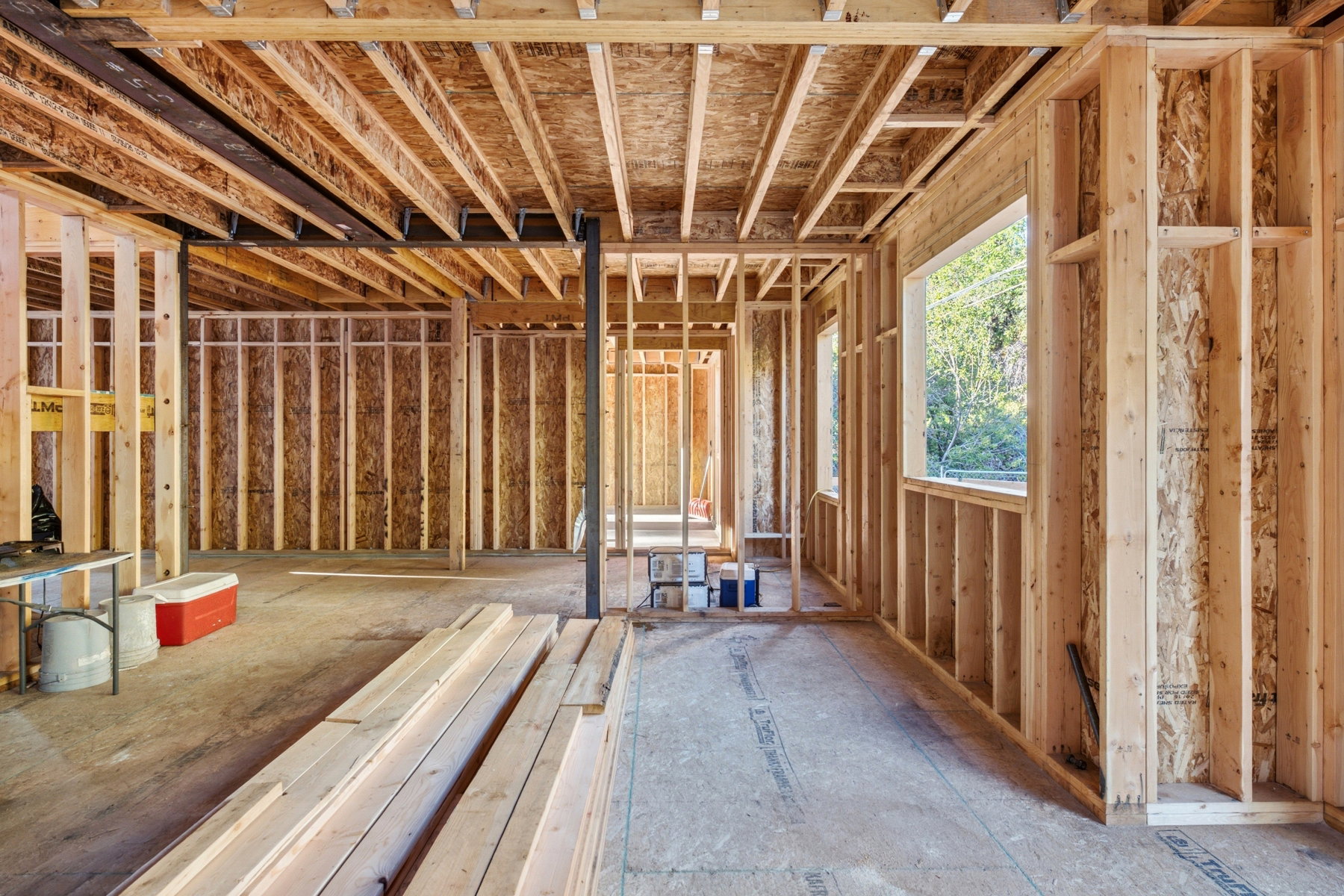 New construction framing with exposed wood studs, floor joists, and a large window opening