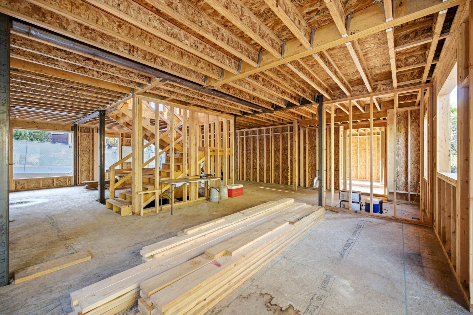 Open-concept framing showcasing structural wood beams, floor joists, and stud walls