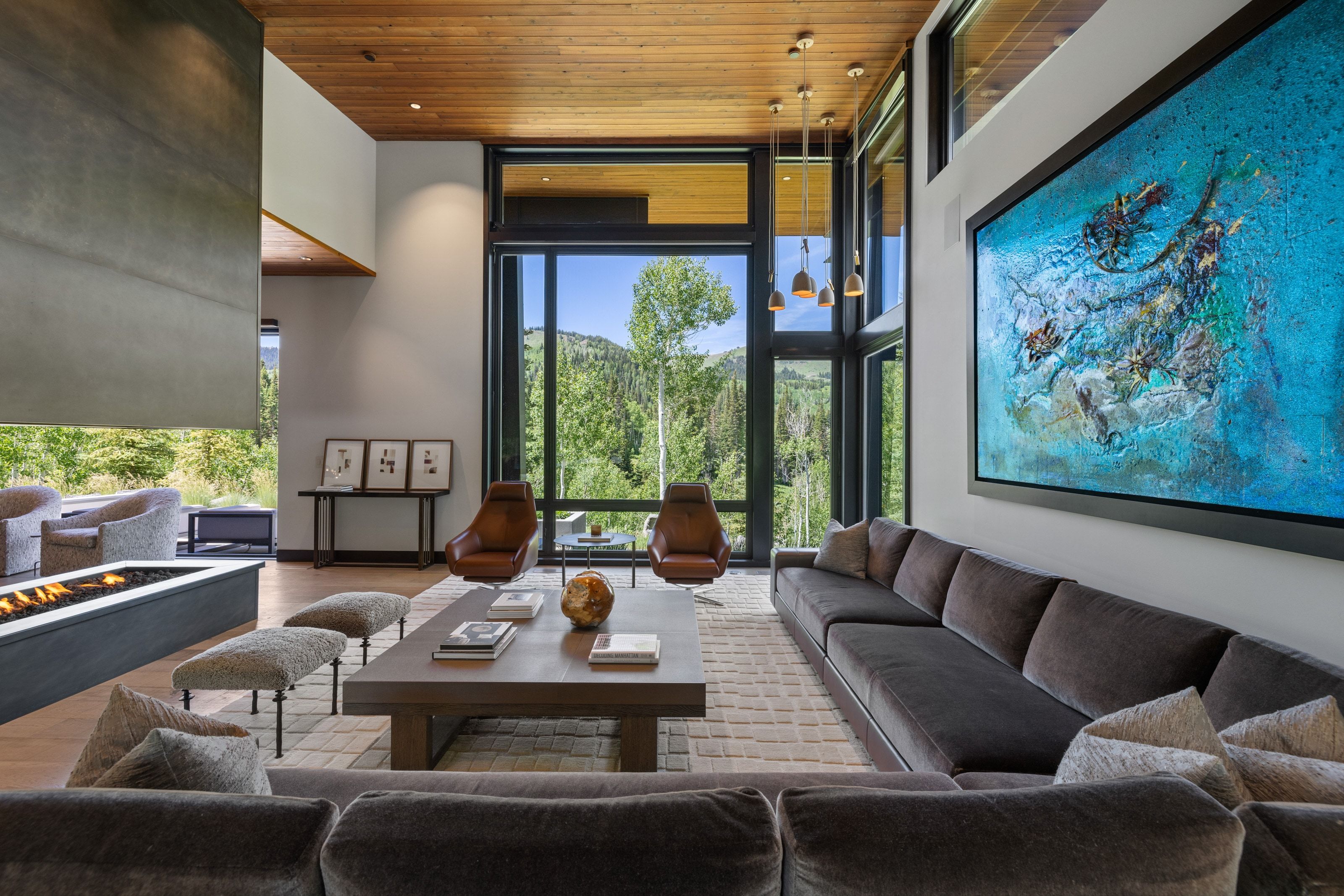 Spacious living area featuring floor-to-ceiling windows, a wood-finish ceiling, an elongated linear fireplace, recessed lighting, and a large format wall-mounted artwork