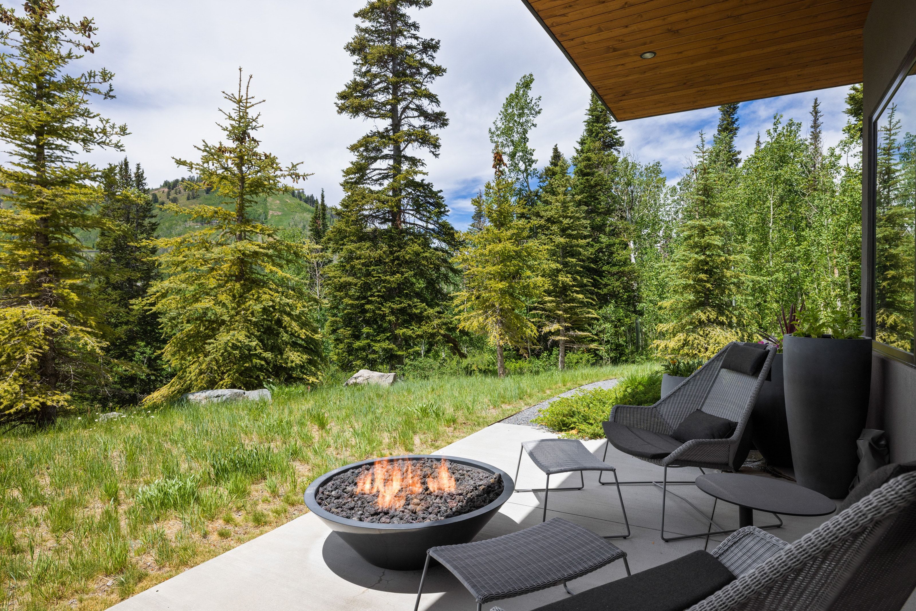 Patio featuring a built-in fire pit with lava rocks, a concrete surface, and a wood-finish ceiling overhang